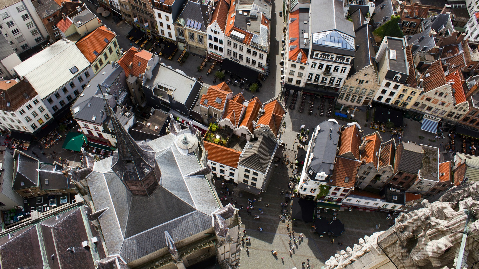 Vista aérea de los tejados del centro histórico de Amberes, Bélgica, con calles, plazas y la aguja de una iglesia gótica.