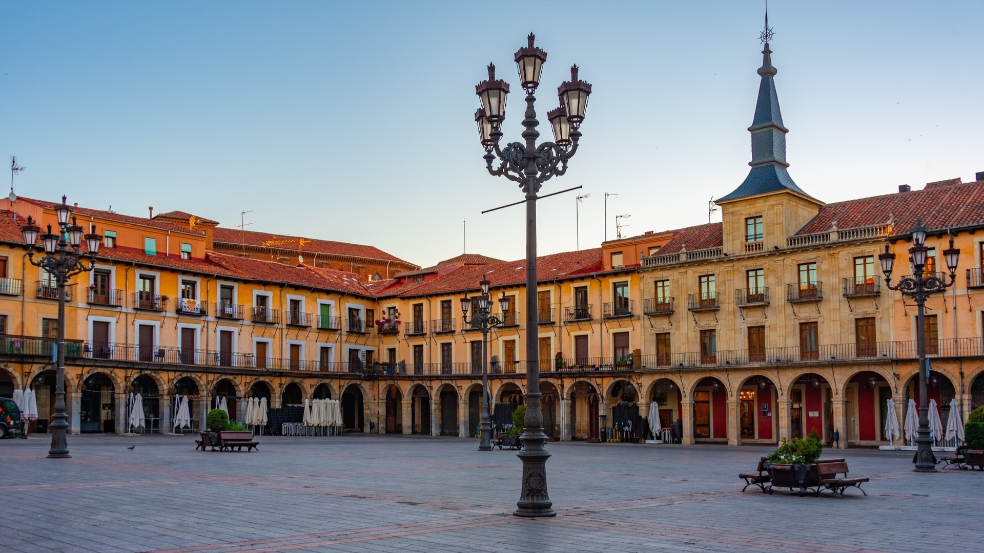 Plaza Mayor de León al atardecer, con edificios porticados, balcones y farolas de hierro, en el centro histórico.