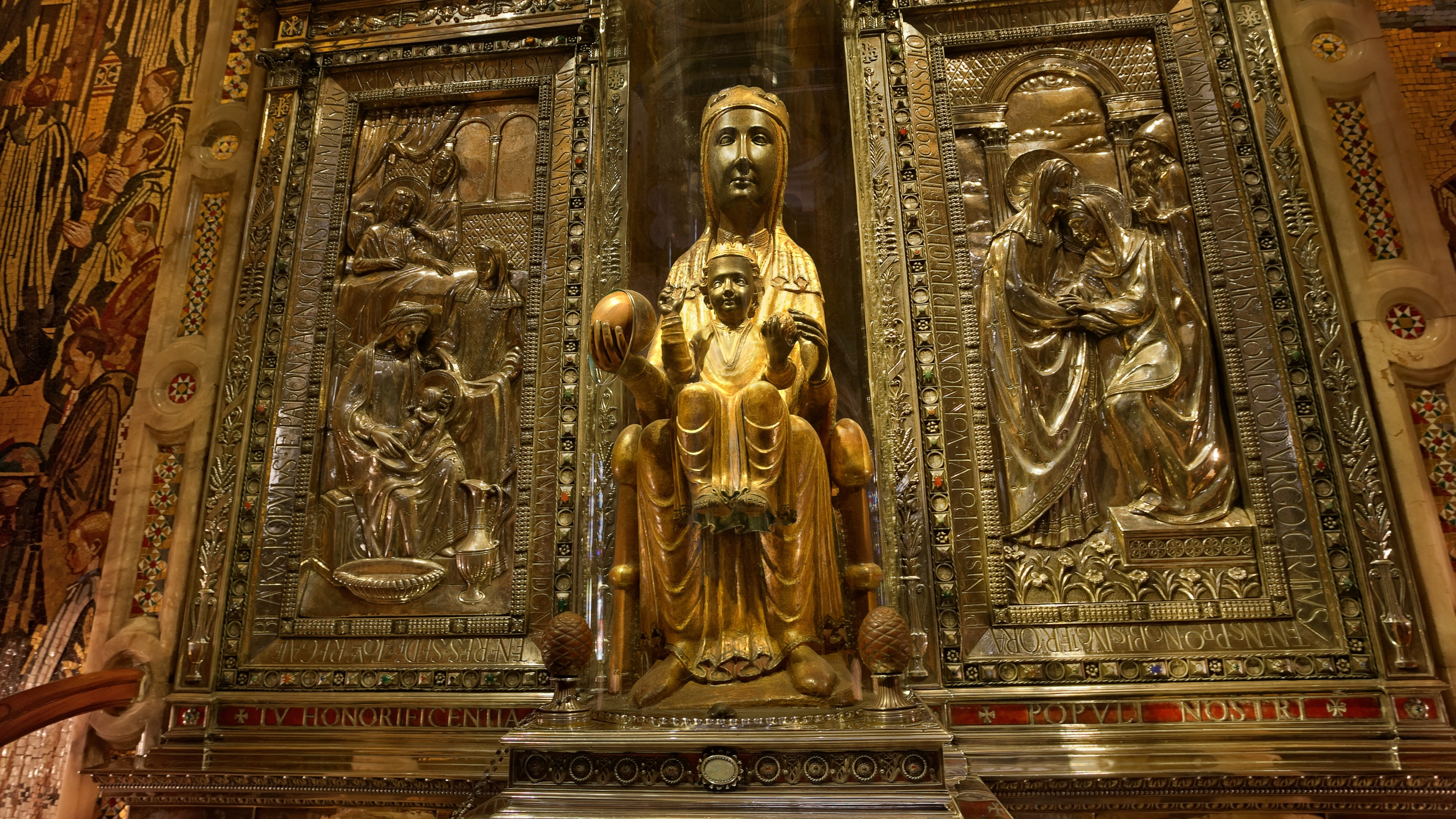 La Moreneta, patrona de Cataluña, estatua de la Virgen de Montserrat en oro, rodeada de relieves metálicos.