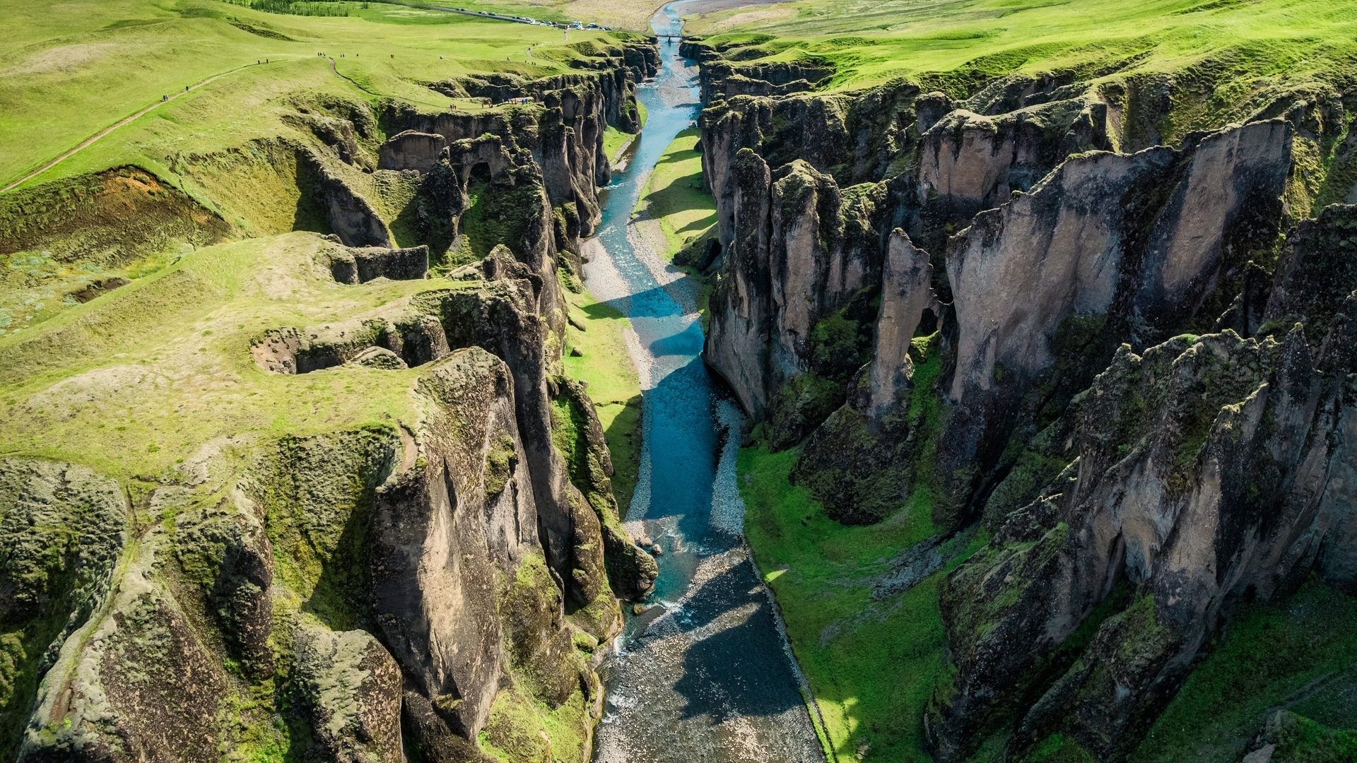 Vista aérea del cañón Fjaðrárgljúfur cerca de Kirkjubæjarklaustur, Islandia, con río azul entre acantilados verdes.