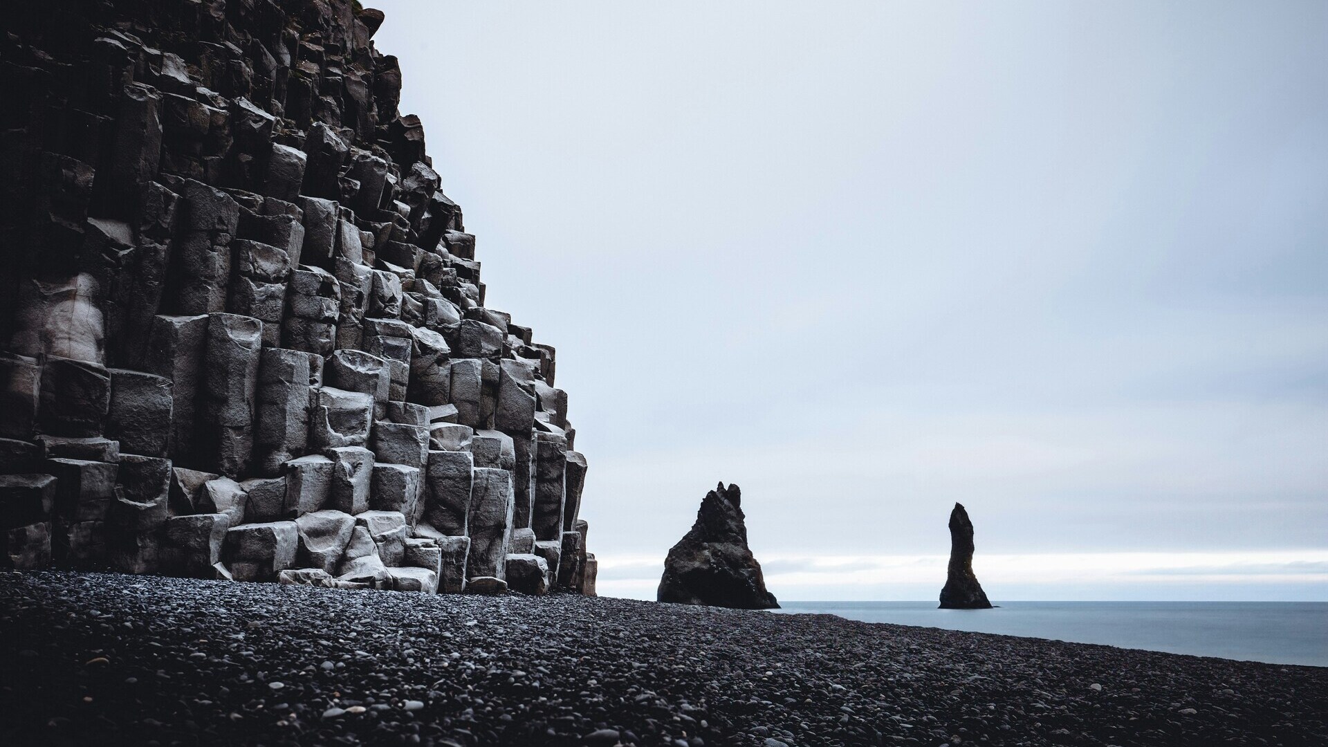 Formaciones de basalto en la playa negra de Reynisfjara, Islandia, frente a los pilares marinos Reynisdrangar.