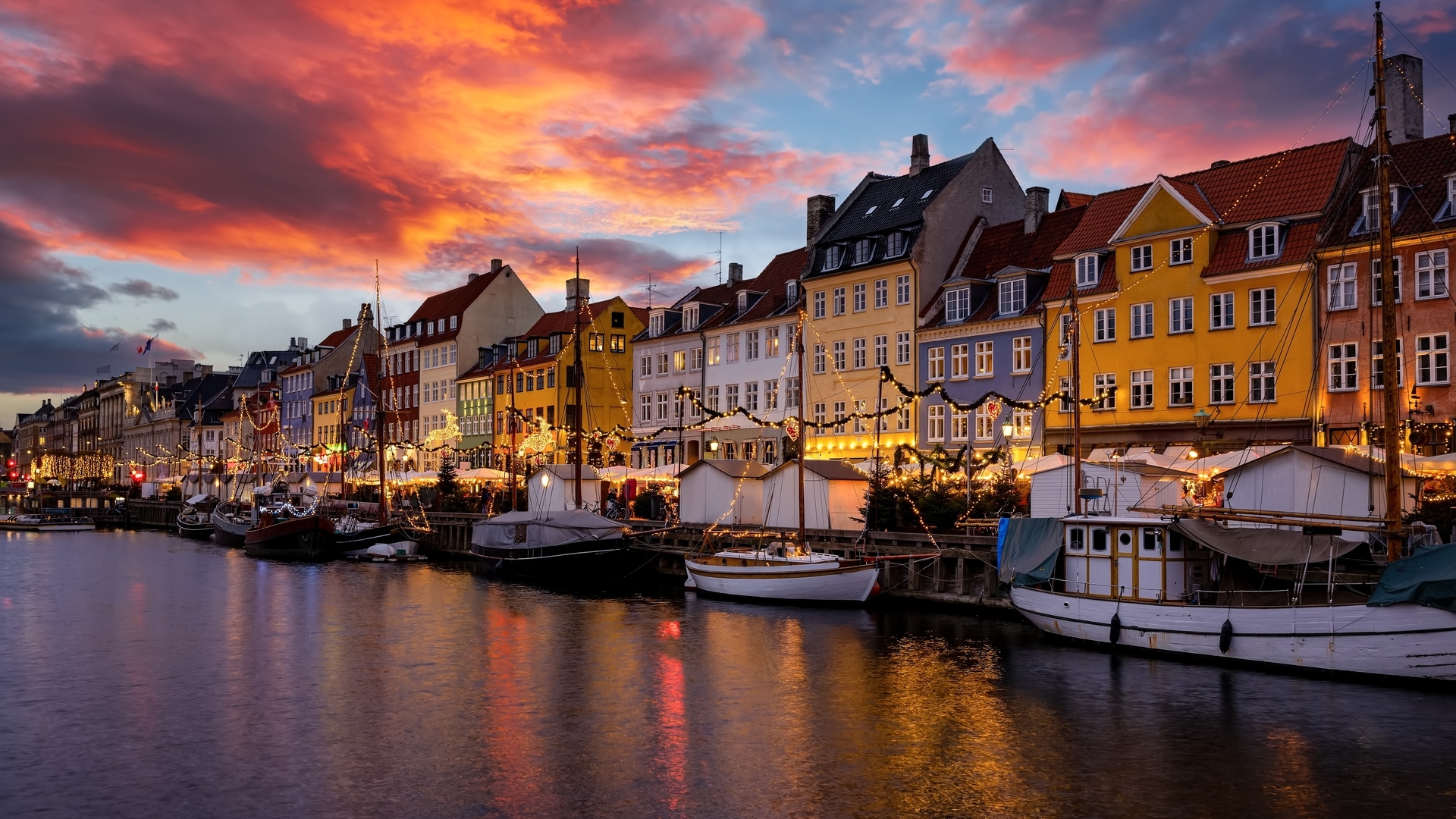 Atardecer navideño en Nyhavn, con las fachadas de colores iluminadas y el canal reflejando el ambiente mágico de Copenhague.