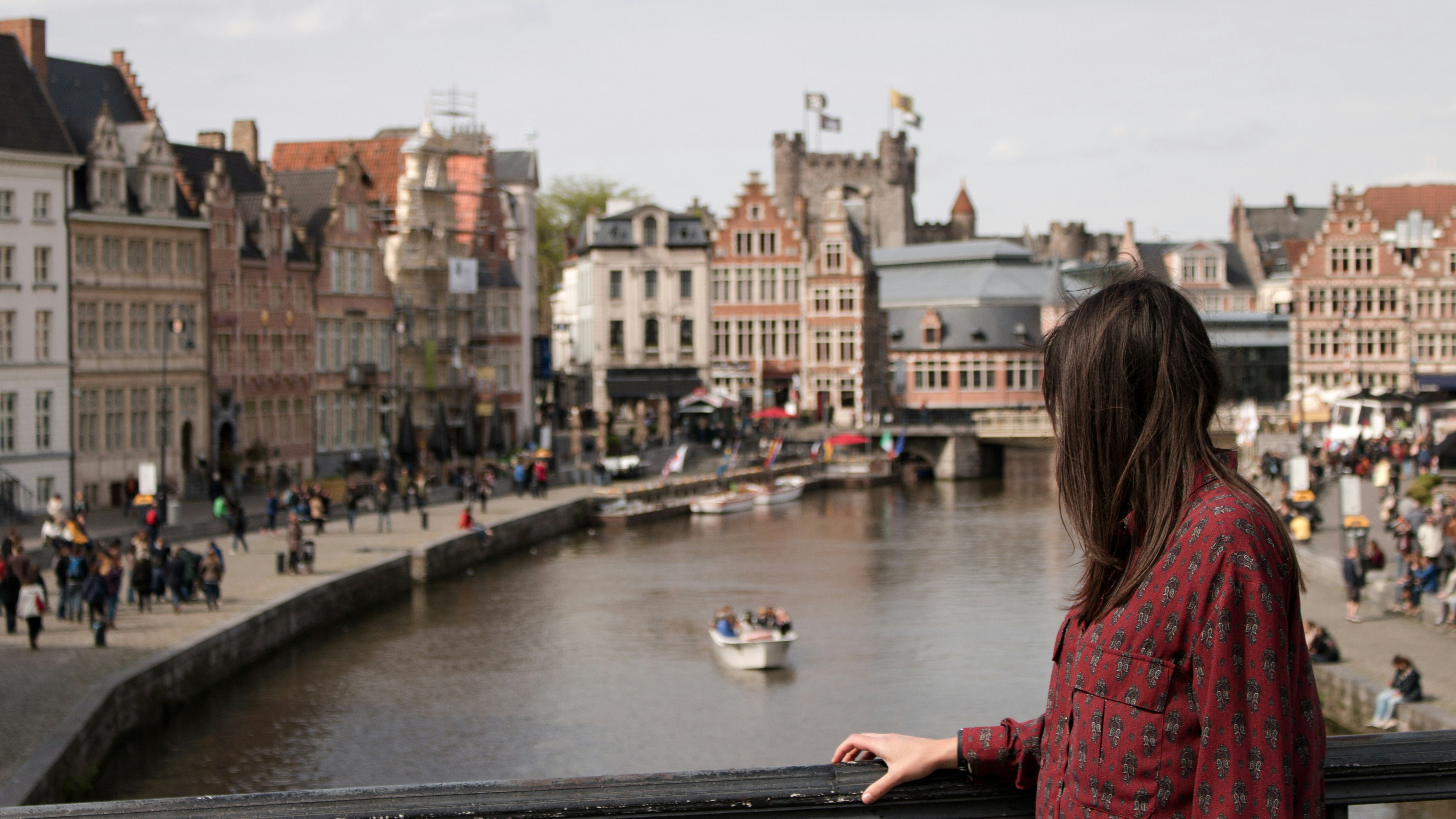 Mujer observando el canal de Gante con el Castillo de los Condes al fondo.