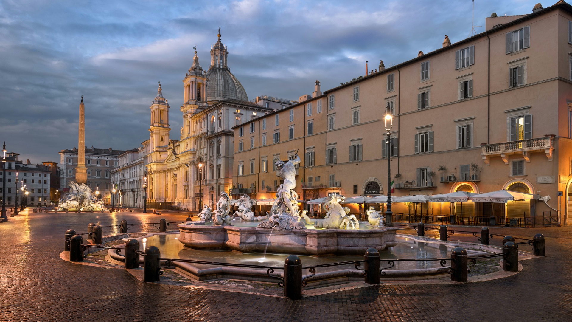 Fuente de Neptuno iluminada en la Piazza Navona de Roma al atardecer.