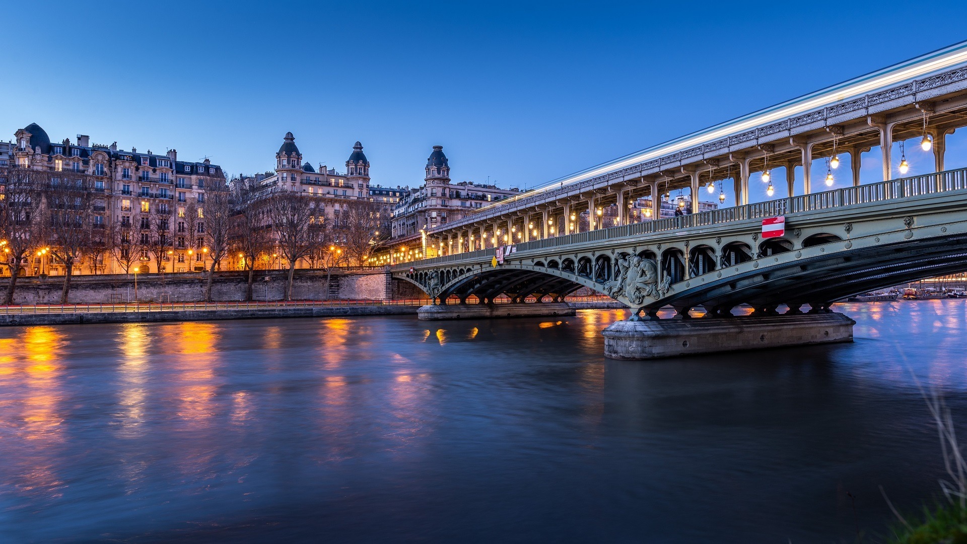 Puente de Bir-Hakeim iluminado sobre el río Sena al atardecer en París.