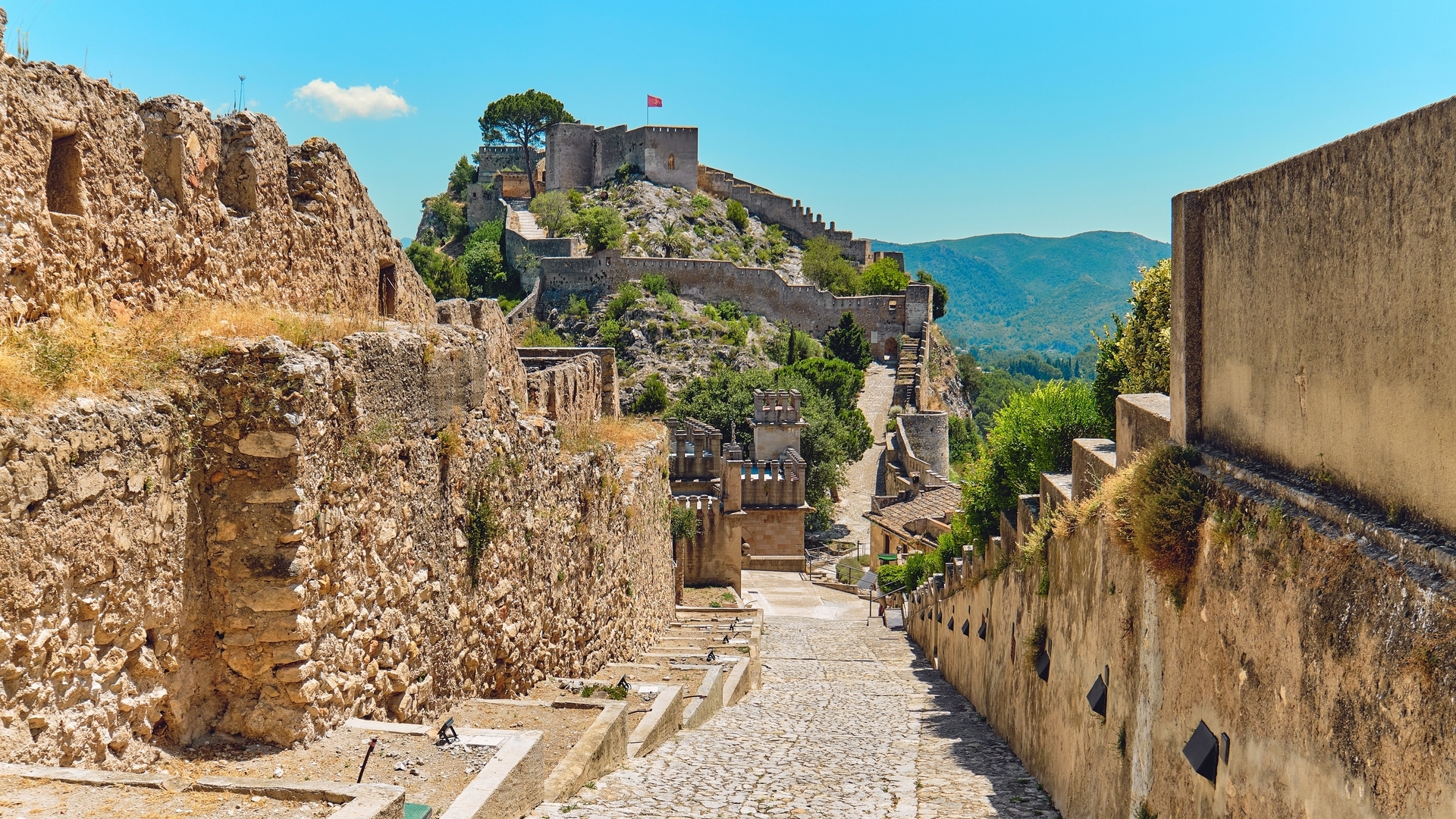 Castillo de Xàtiva sobre una colina con murallas y vistas a las montañas.