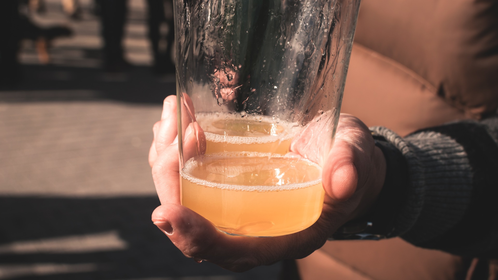 Mano sosteniendo un vaso de sidra natural escanciada en Cangas del Narcea.