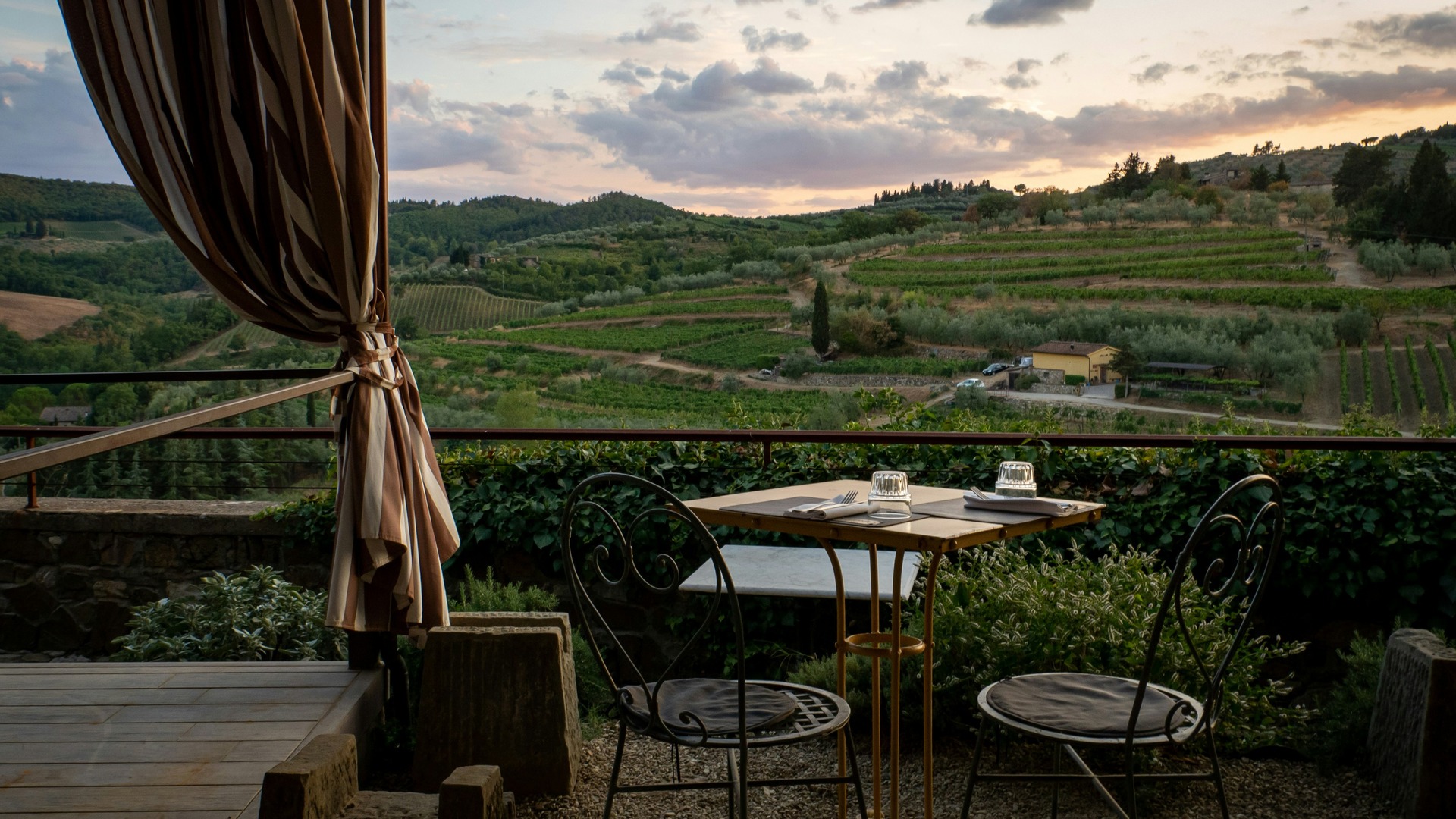 Mesa servida en una terraza con vistas a los viñedos de la Toscana
