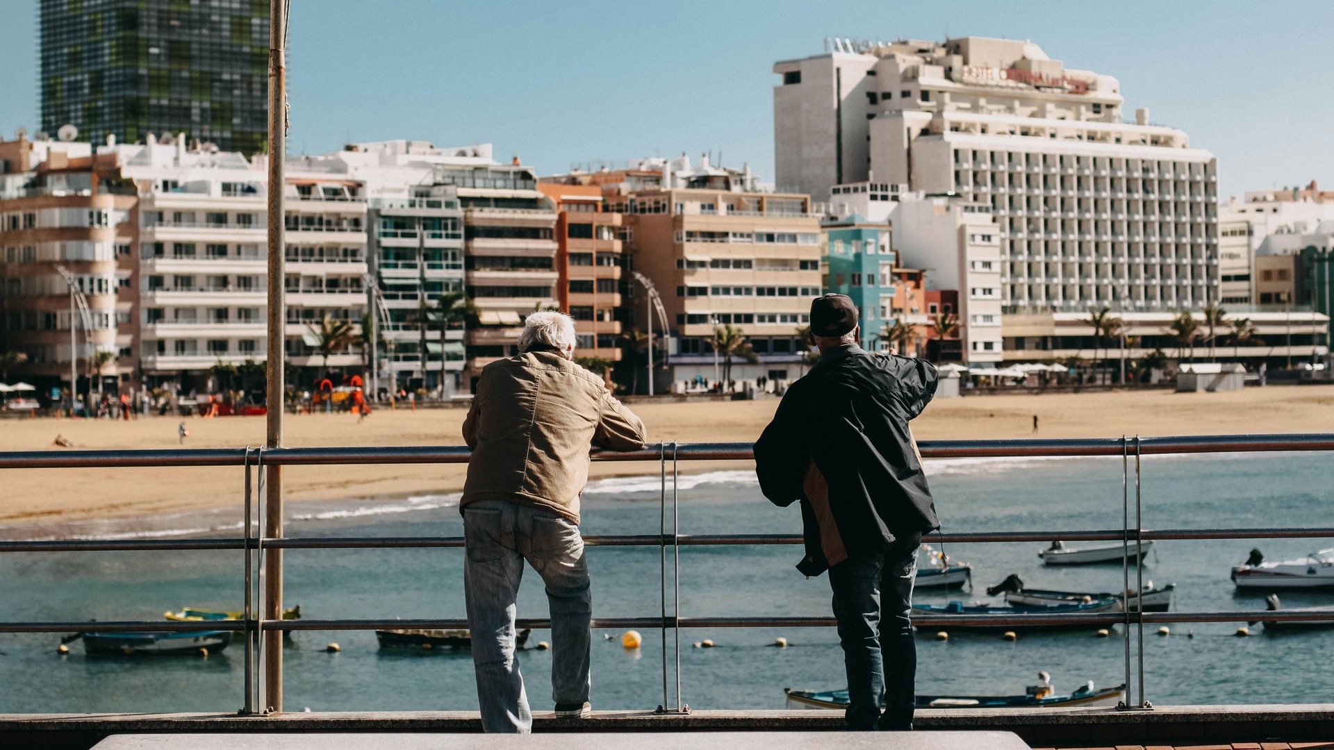 Personas mirando el mar y barcas en la Playa de Las Canteras, Las Palmas.