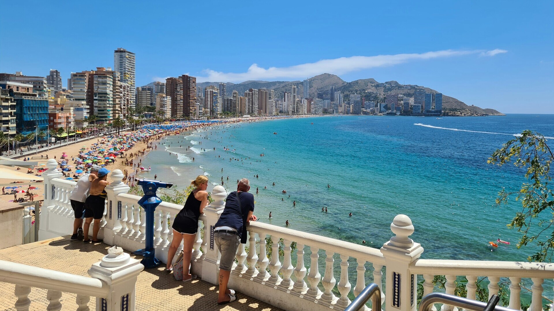 Personas observando la playa de Levante desde el mirador del paseo en Benidorm