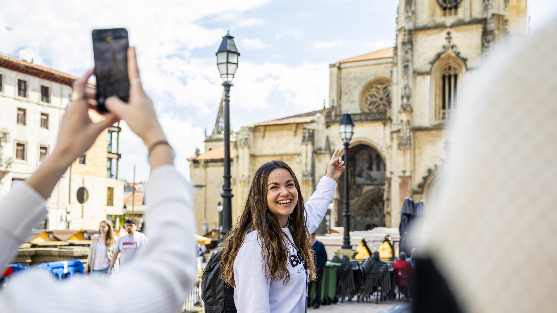 La guía señala la Catedral de Oviedo mientras le toman una foto.