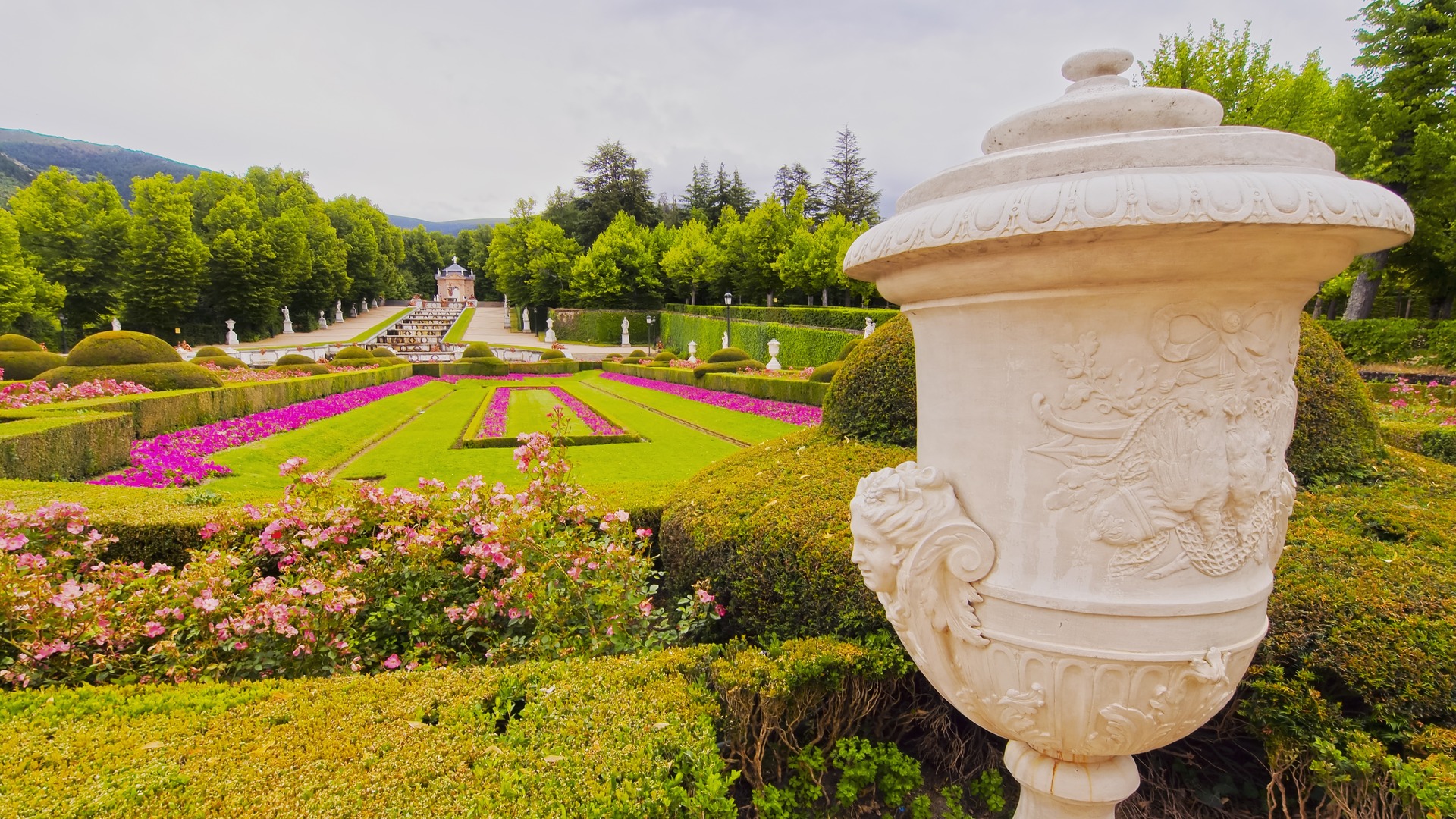 Urna de mármol en primer plano y parterres rosados en el Palacio de la Granja