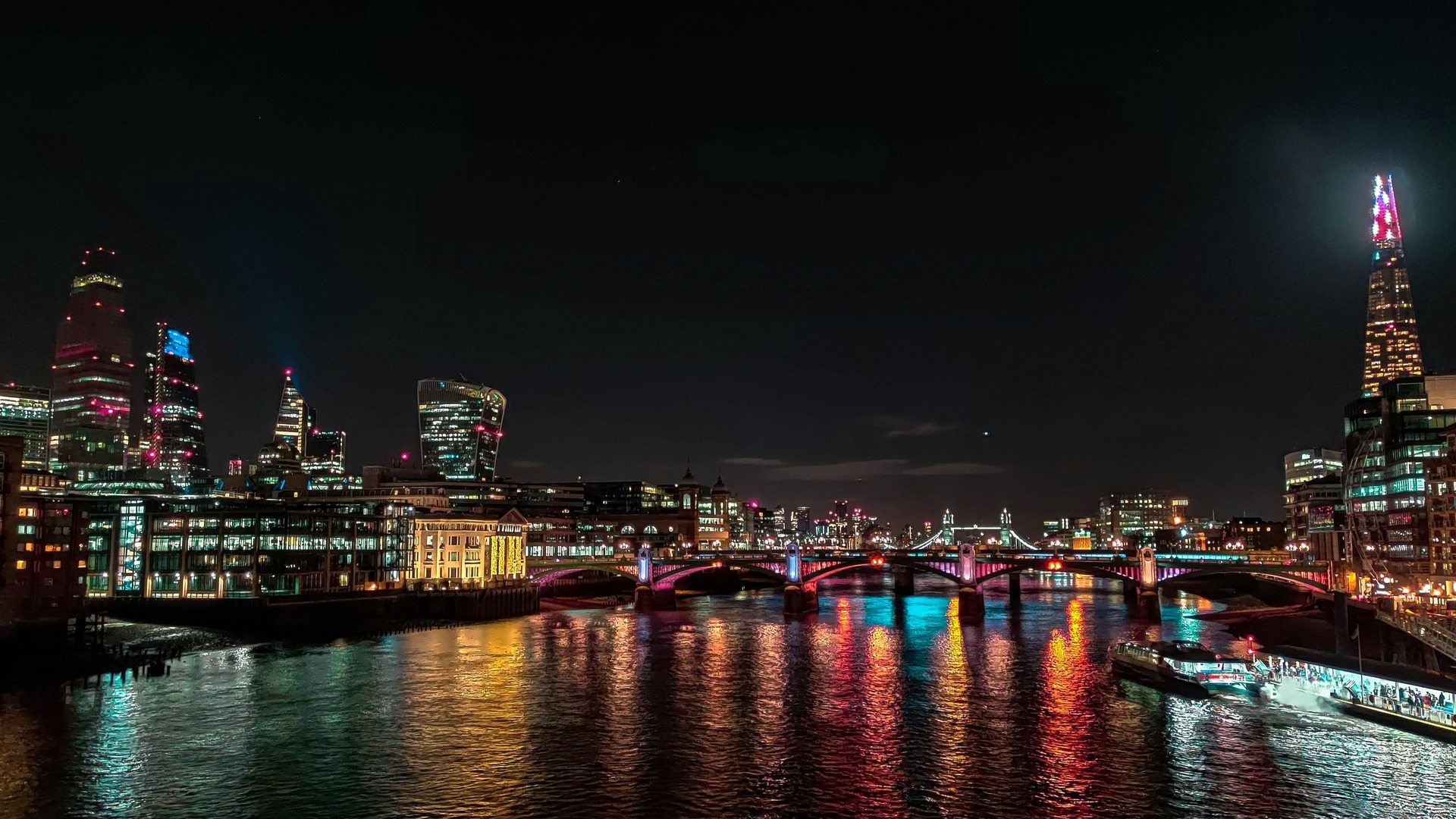 Puente de Southwark y rascacielos iluminados sobre el río Támesis de noche.