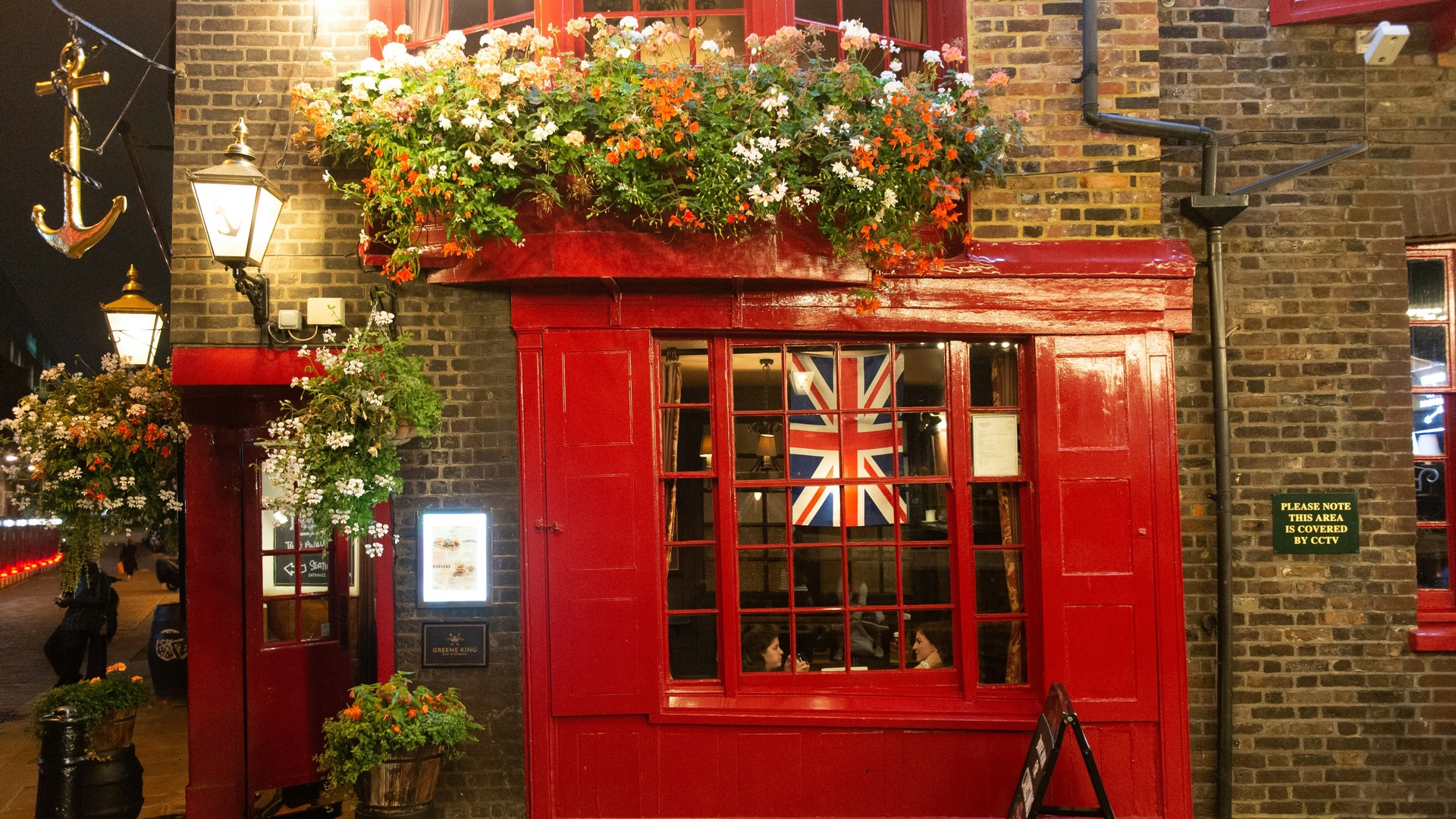 Fachada de un pub tradicional con flores y la bandera británica en Londres.