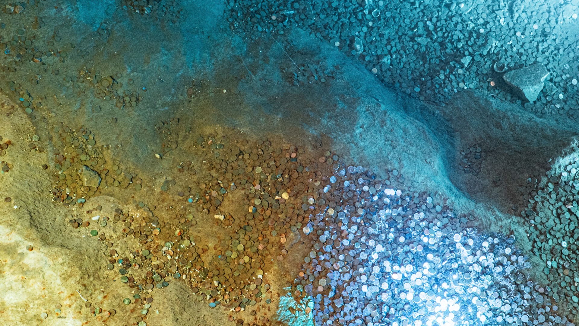 Monedas acumuladas en el fondo de la Cueva del Tesoro en Rincón de la Victoria.