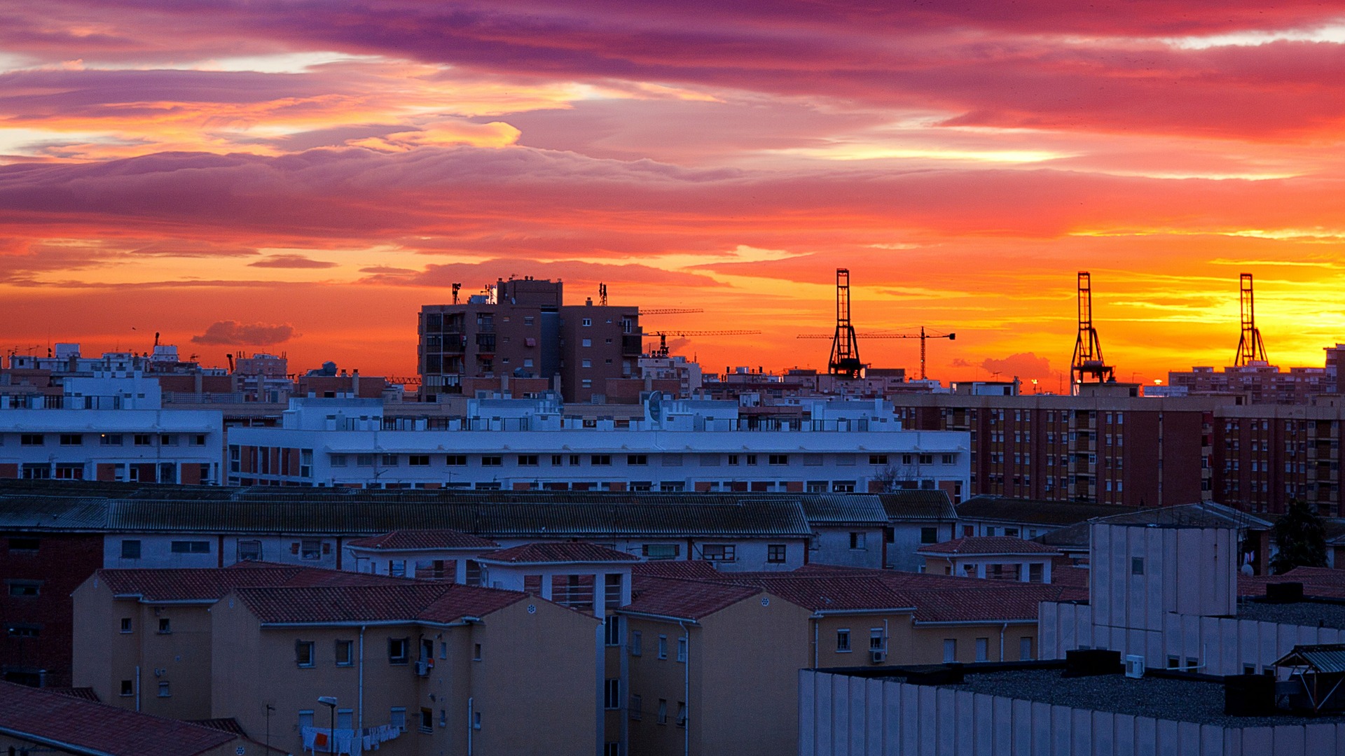 Atardecer sobre edificios y grúas del puerto de Málaga, España.