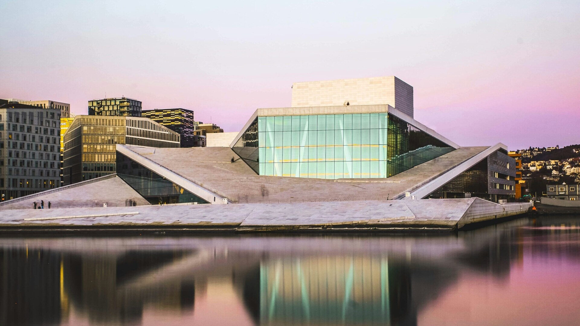 Ópera de Oslo, Noruega, al atardecer, con su arquitectura moderna reflejada en las tranquilas aguas del fiordo.