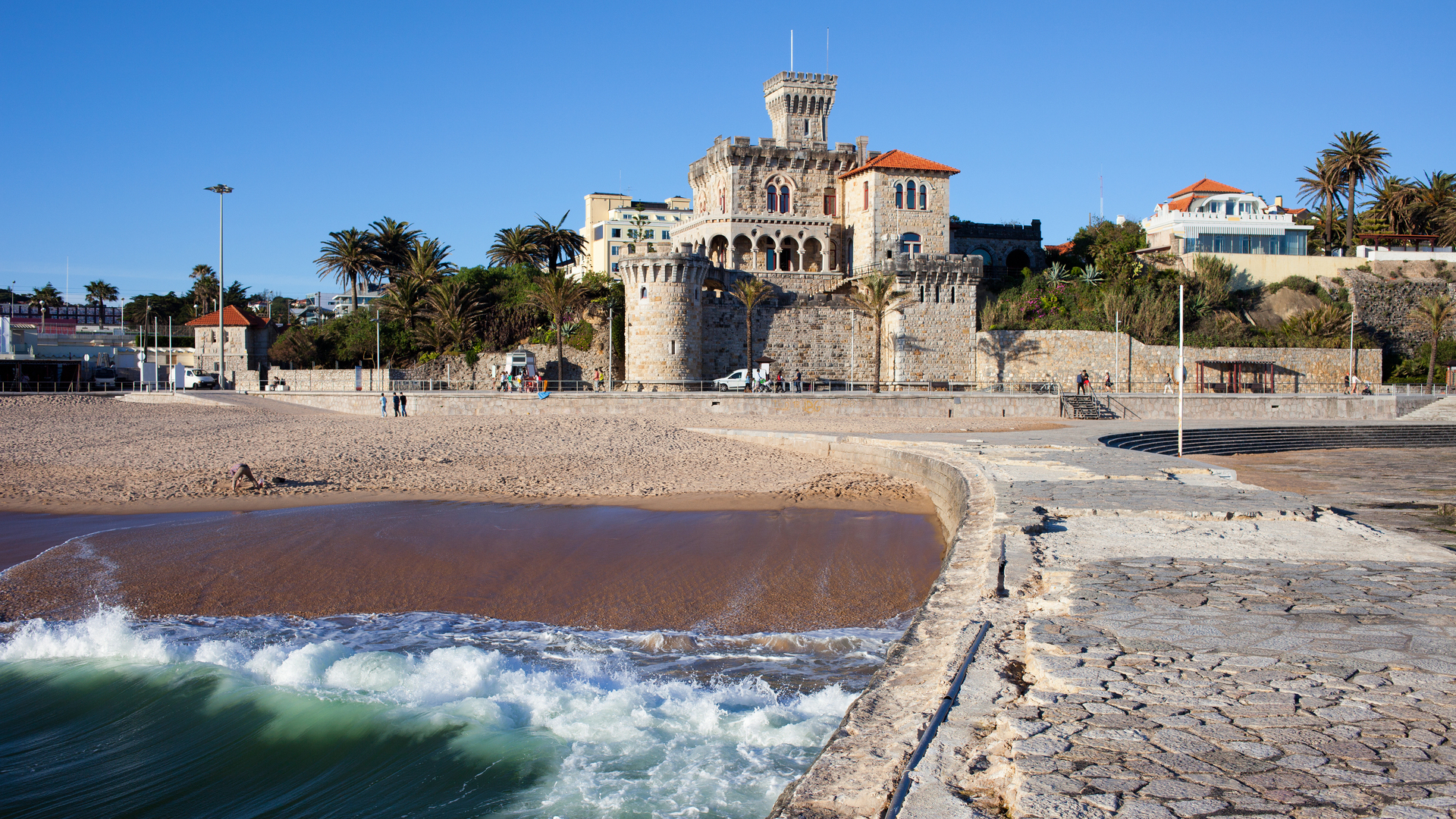 Playa de Tamariz con el castillo de Estoril junto al mar en un día despejado.
