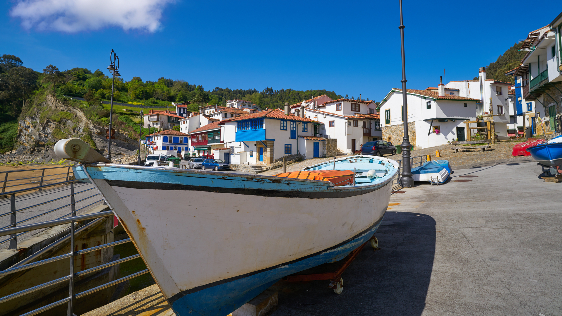 Barca en el puerto de Tazones frente a casas blancas tradicionales