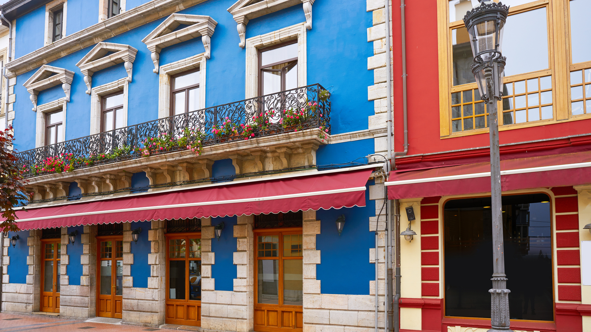Fachadas coloridas con balcones de flores en una calle del centro de Llanes