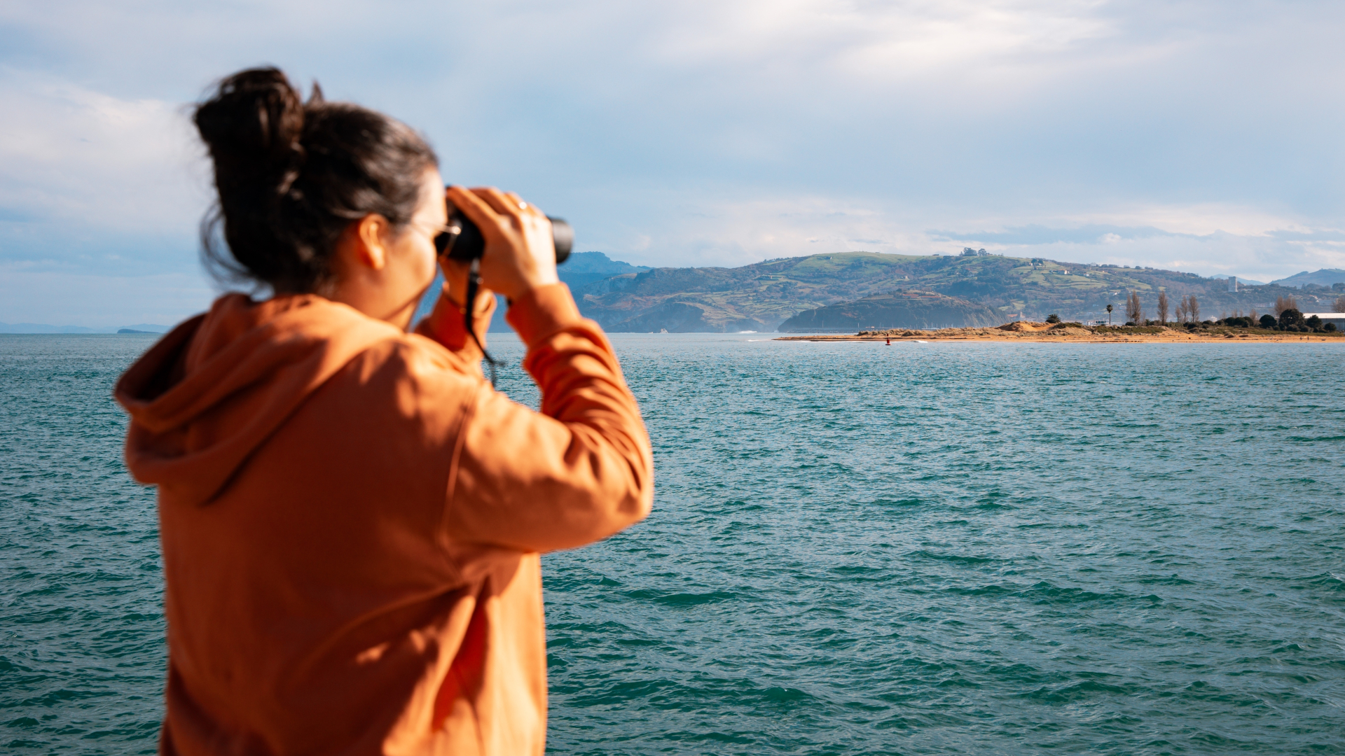 Persona con prismáticos mirando la costa en Santander, Cantabria.