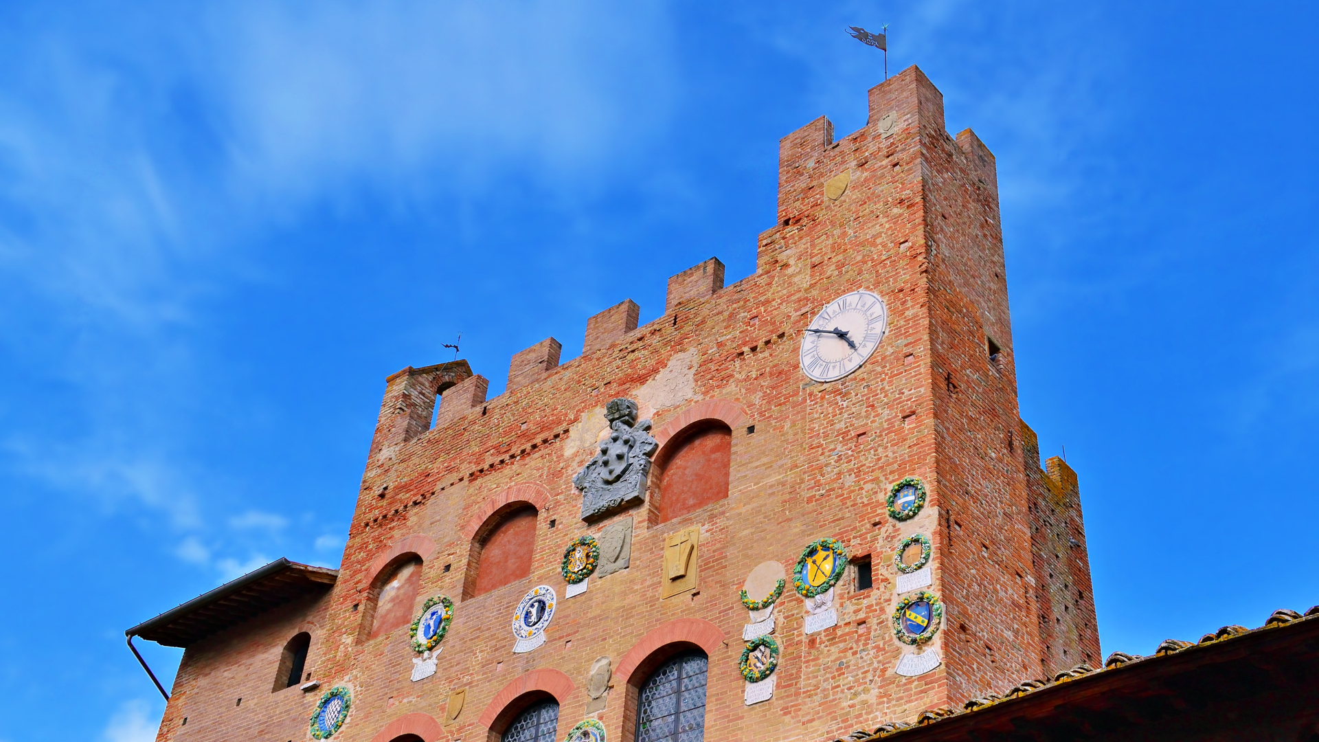 Torre medieval con escudos heráldicos en un pueblo de la Toscana, Italia
