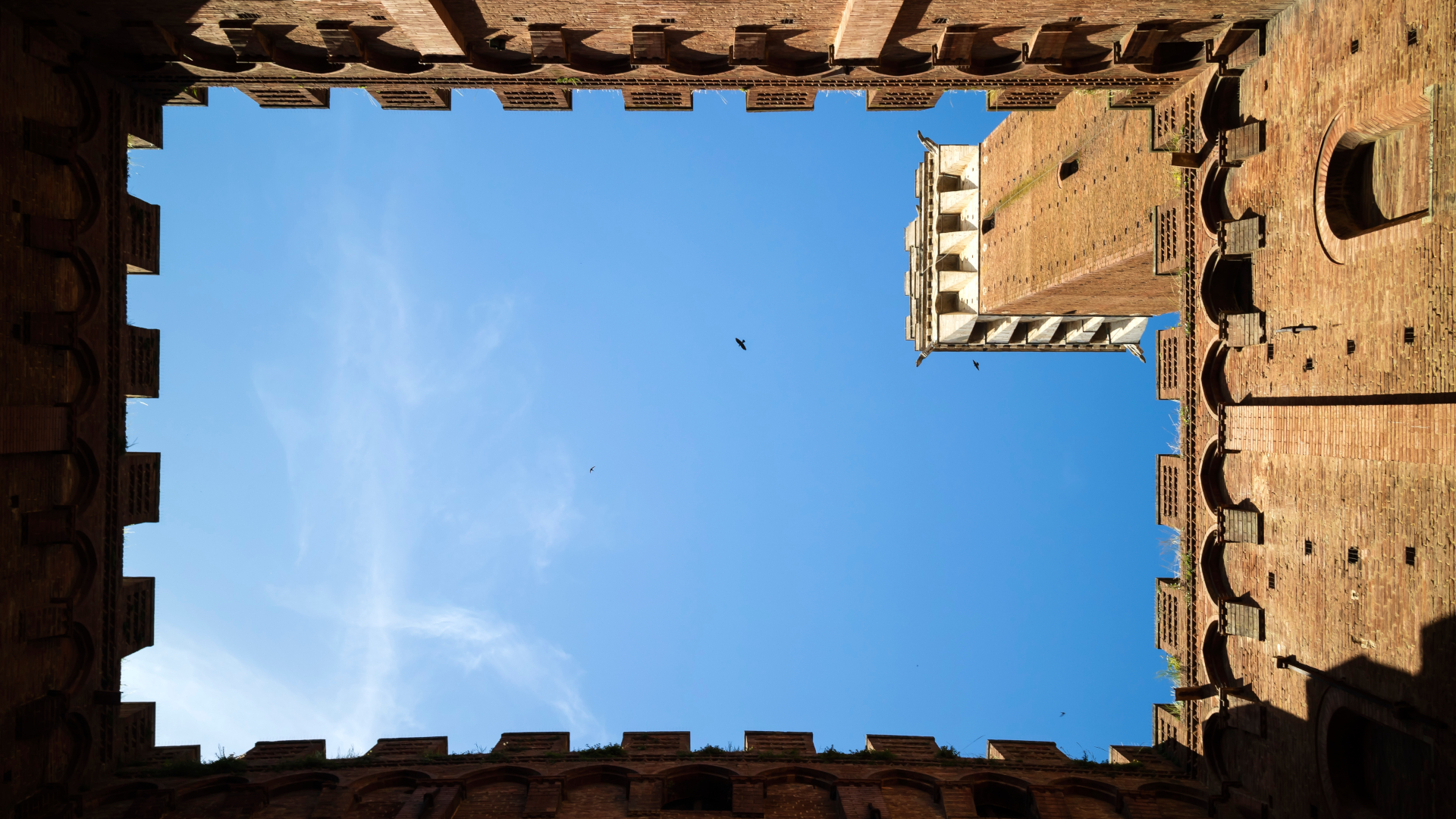 Vista desde patio medieval con torre y cielo azul en la Toscana, Italia