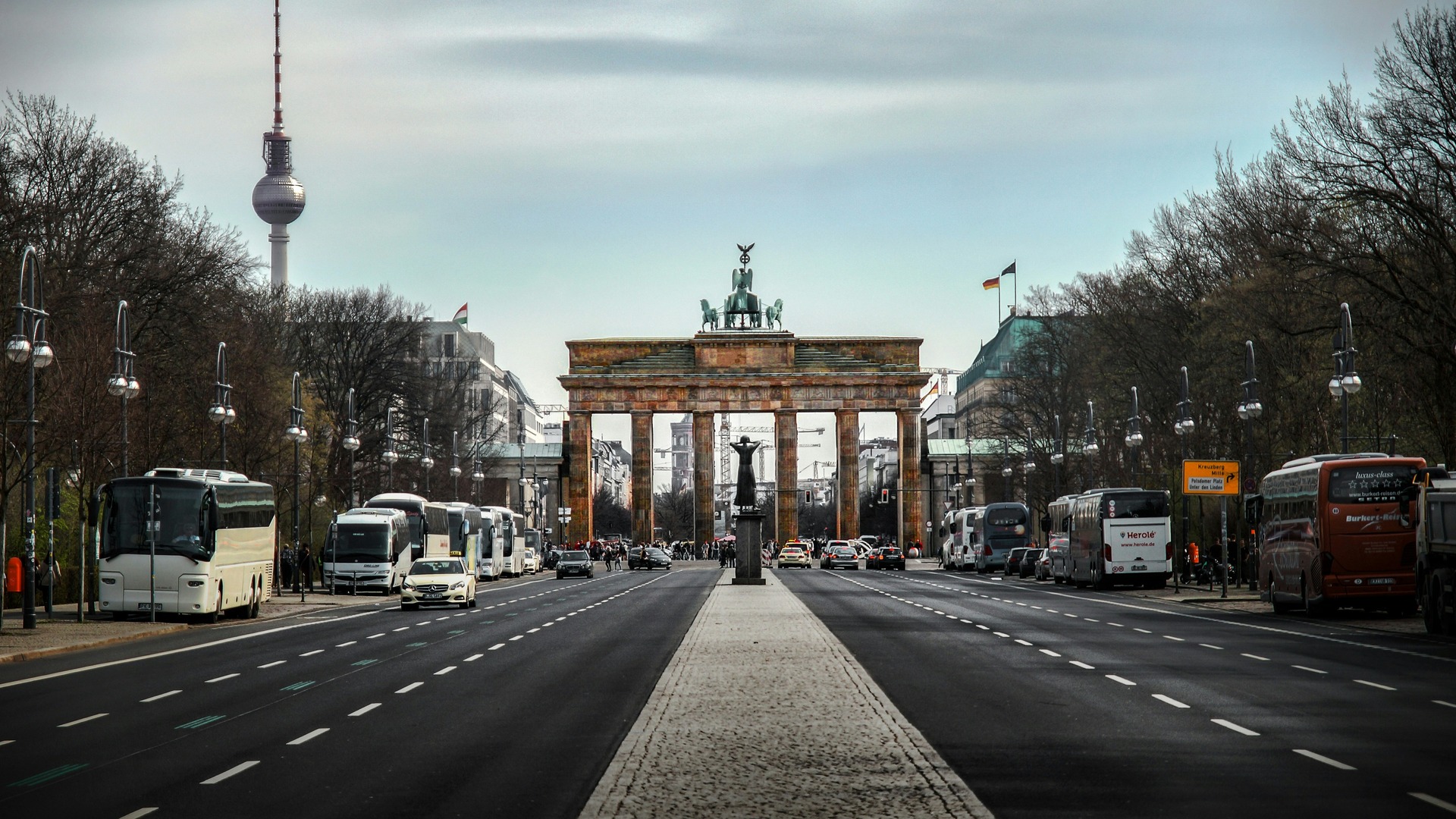 Puerta de Brandeburgo y Torre de la Televisión desde calle con buses en Berlín.