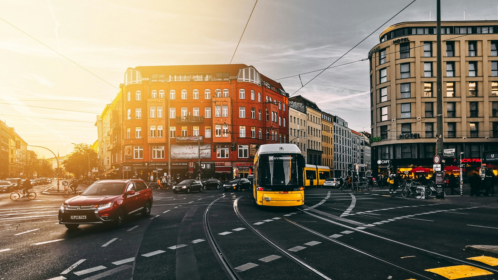 Tranvía amarillo circulando por intersección urbana de Berlín al atardecer.
