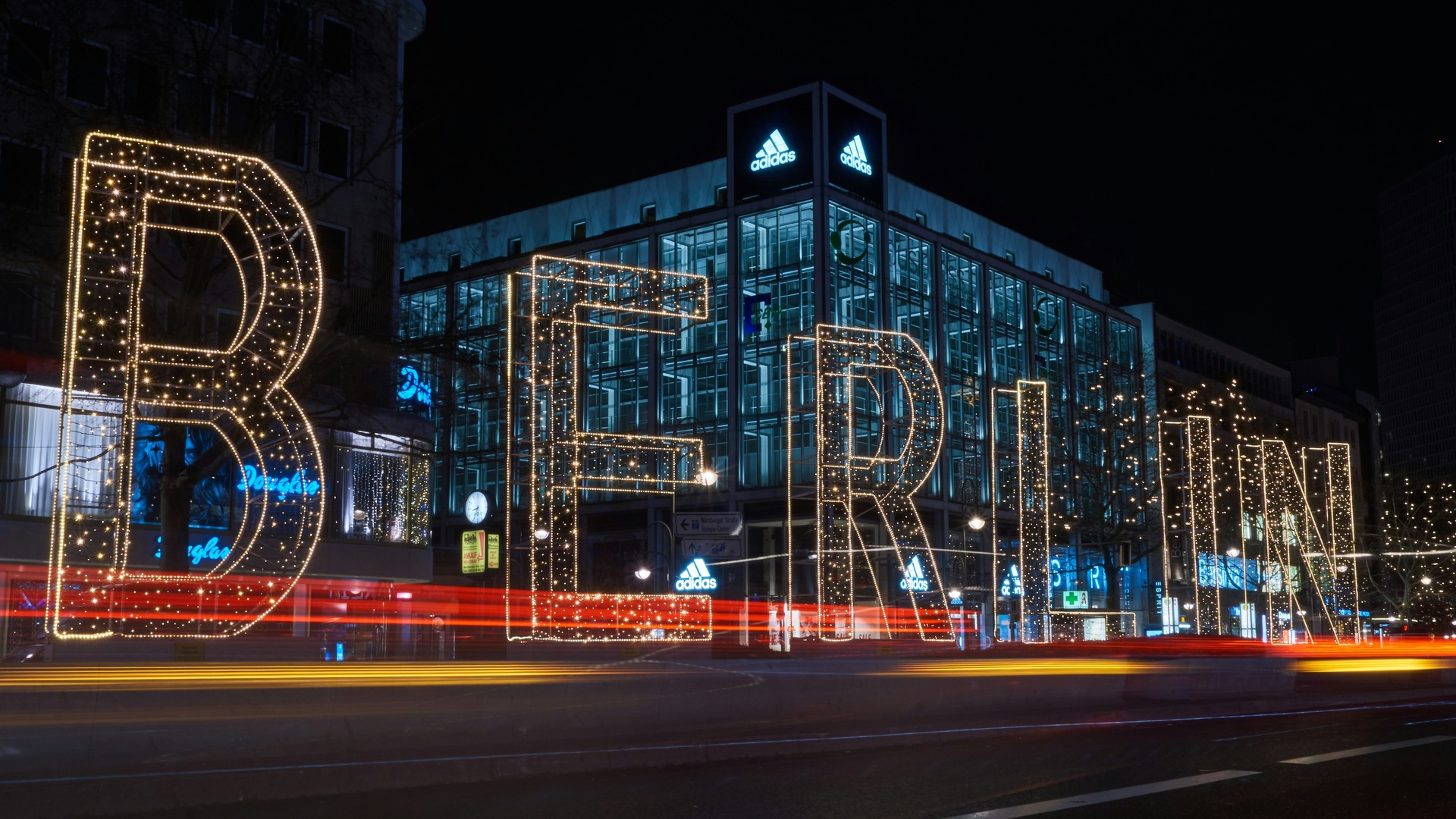 Letrero luminoso gigante de BERLÍN en una calle nocturna con estelas de coches.