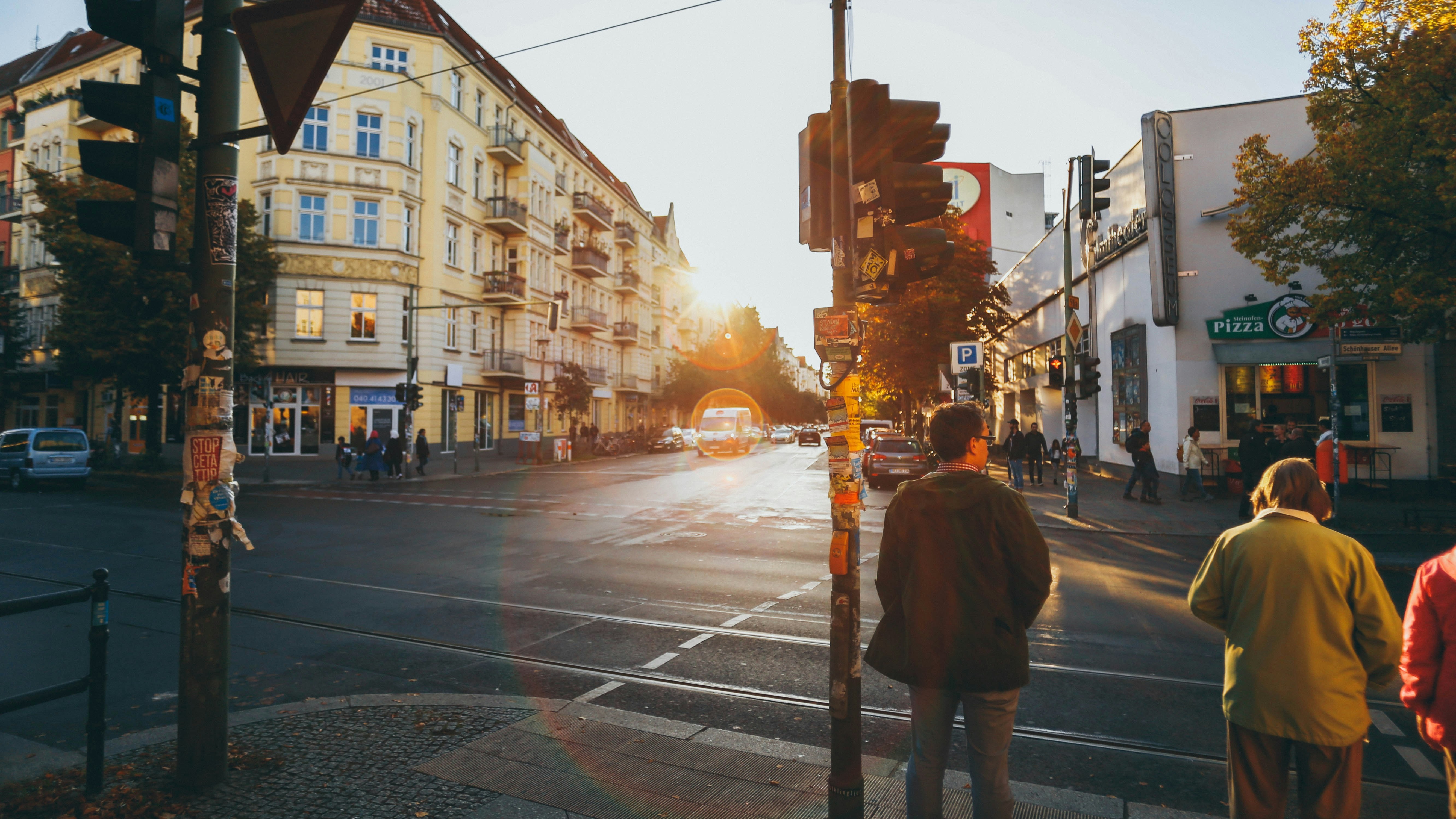 Cruce urbano en Berlín con luz de atardecer, semáforos y arquitectura clásica.