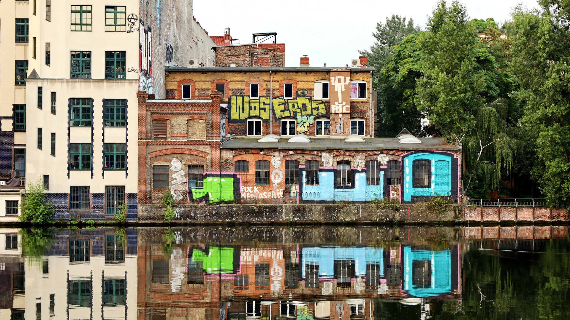 Edificios industriales con grafiti reflejados en el río Spree en Berlín.