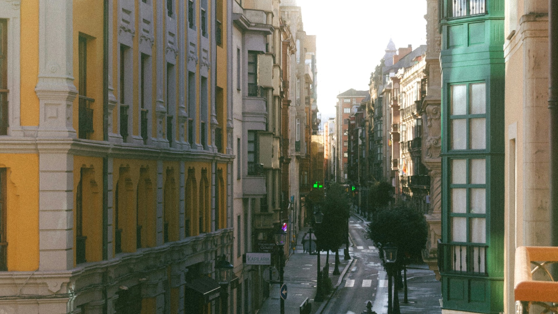 Calle comercial del centro de Gijón con arquitectura clásica y galerías verdes.