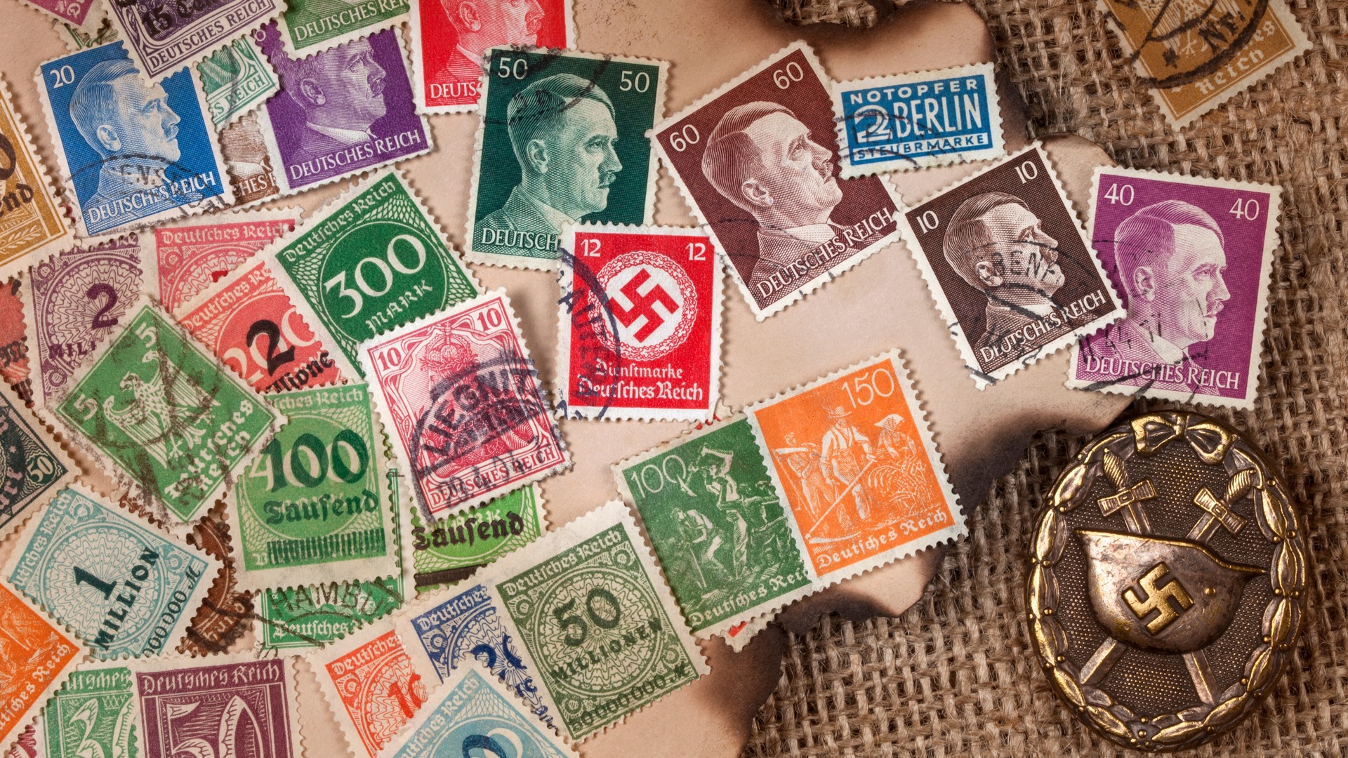 Colección de sellos postales del Tercer Reich y medalla con esvástica nazi.