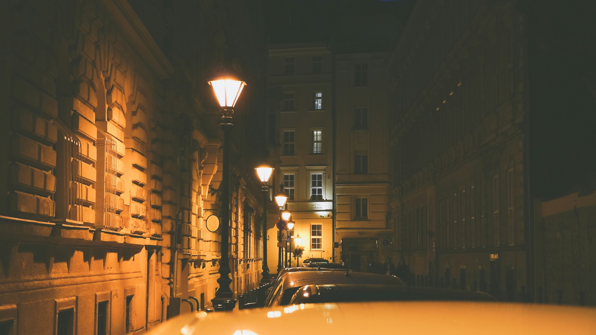Calle estrecha de Budapest de noche con farolas clásicas y arquitectura antigua.