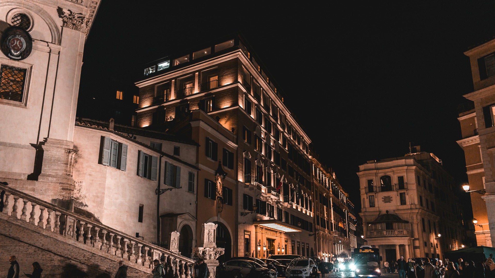 Edificios clásicos y escalinatas iluminadas en una calle de Roma por la noche.