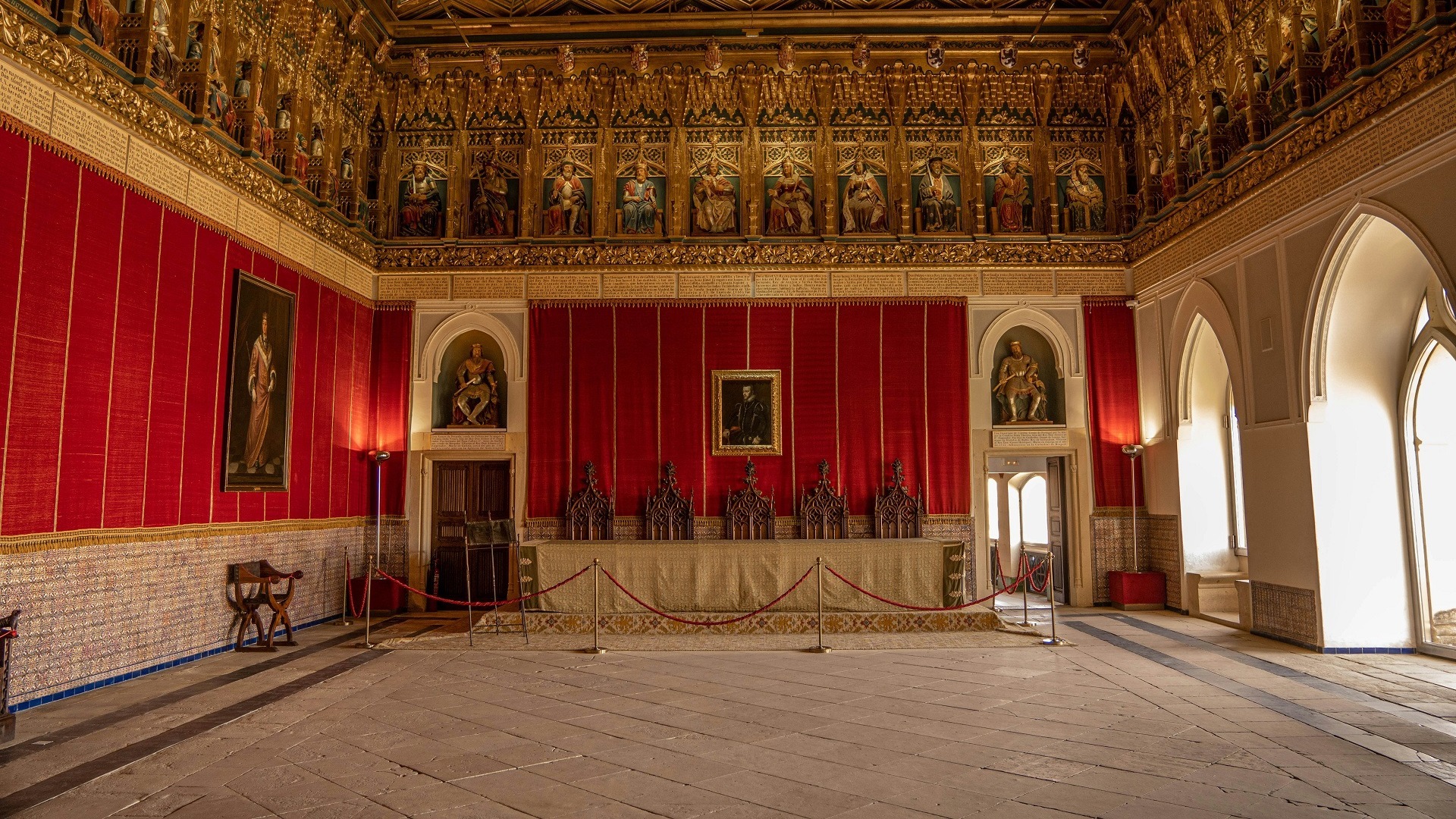 Sala del Trono en el Alcázar de Segovia con friso de reyes y tapices rojos.