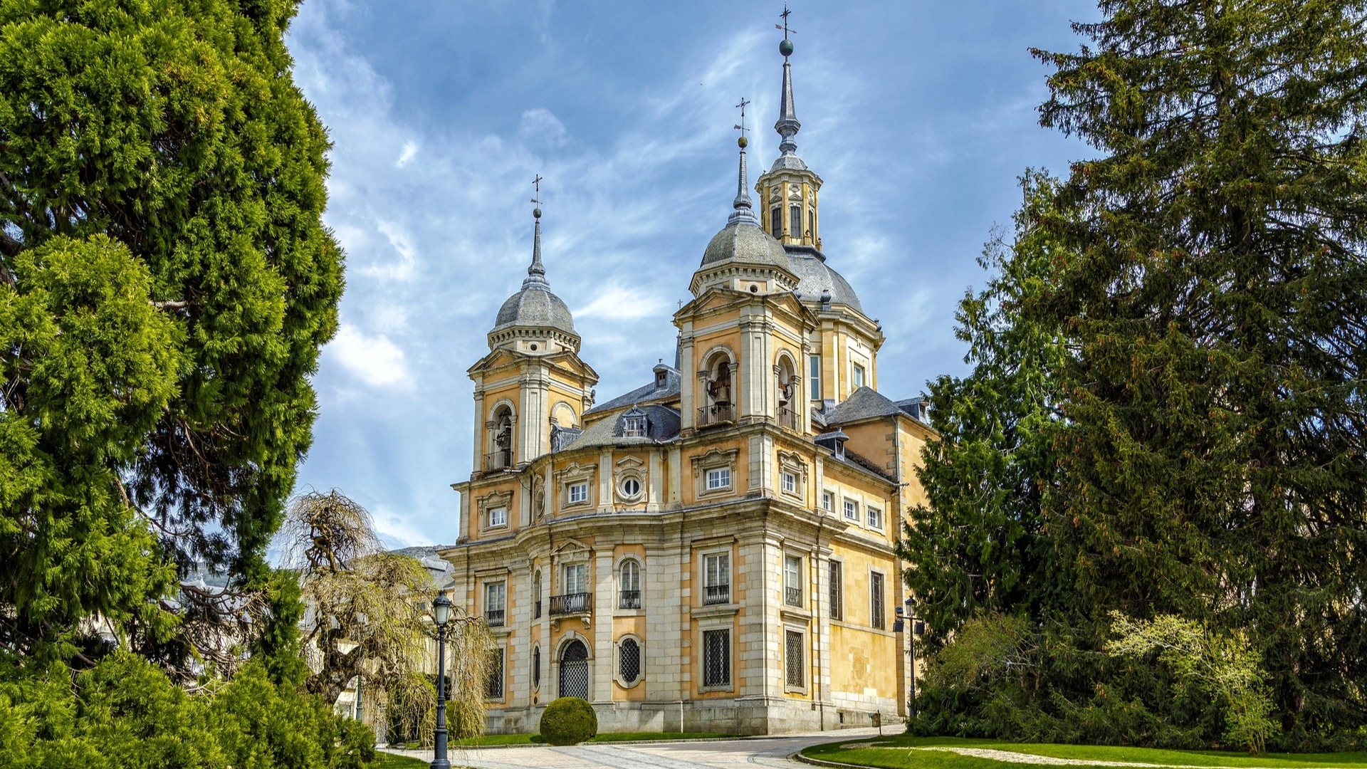 Colegiata del Palacio Real de La Granja de San Ildefonso entre árboles verdes.