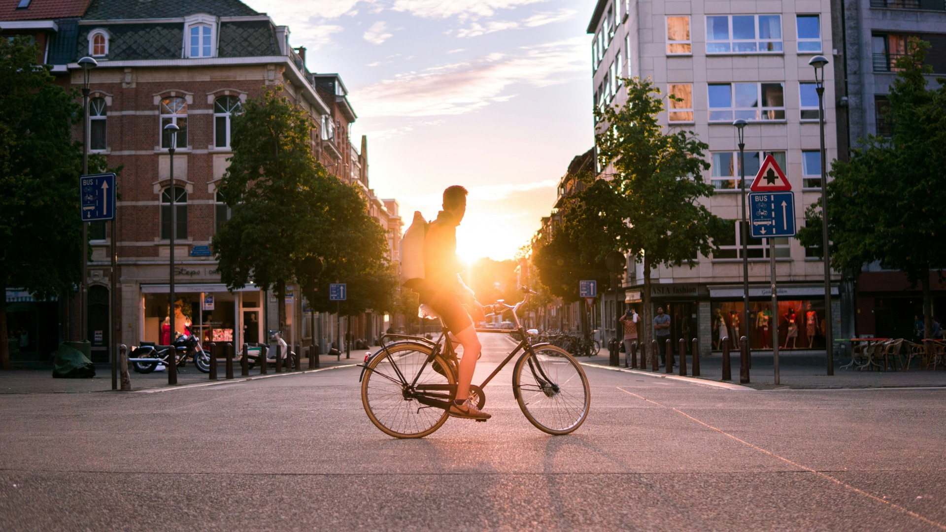 Ciclista cruzando una calle de Bruselas durante el atardecer.