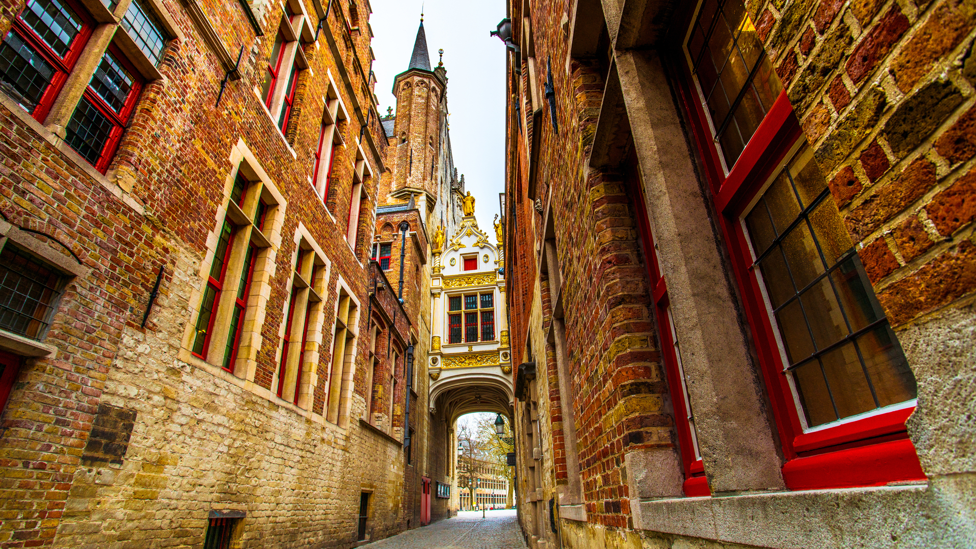 Callejón empedrado con arquitectura gótica y arco ornamental en Brujas.