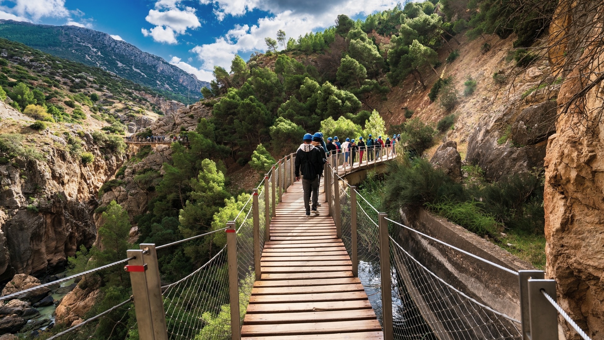 Grupo de visitantes con cascos azules caminando por el Caminito del Rey
