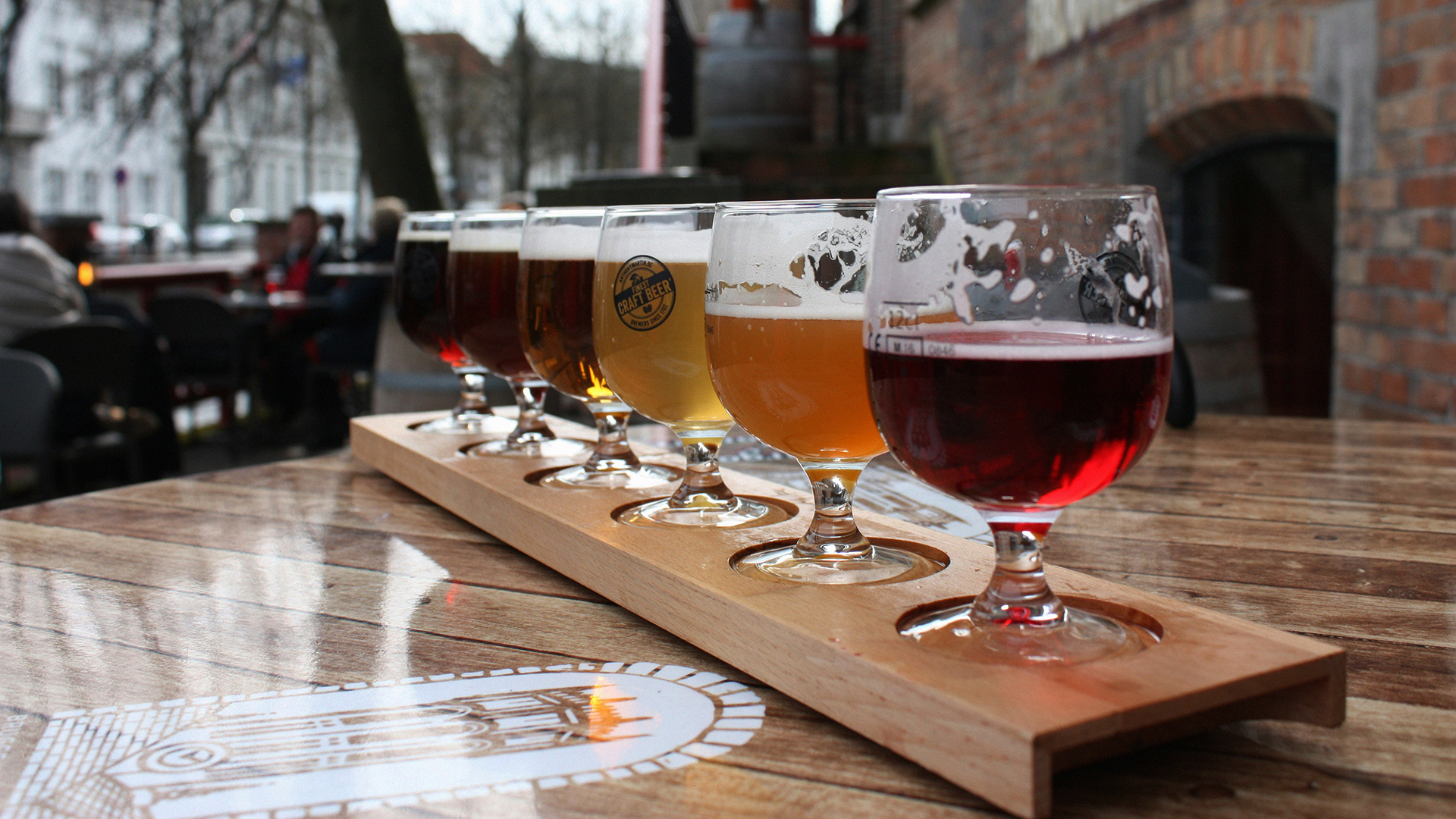 Cata de seis cervezas artesanales en tabla sobre terraza urbana en Bélgica