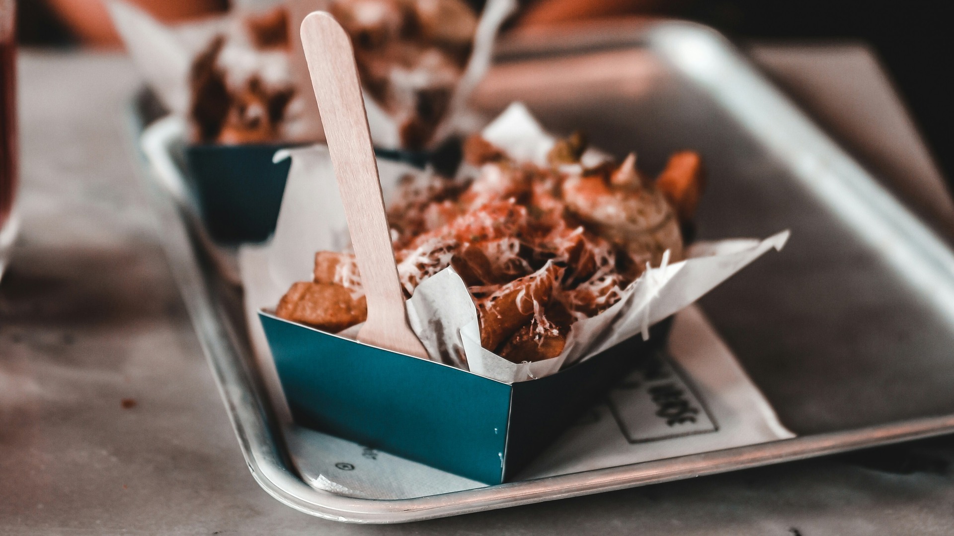 Patatas fritas servidas en bandeja con salsa y queso rallado