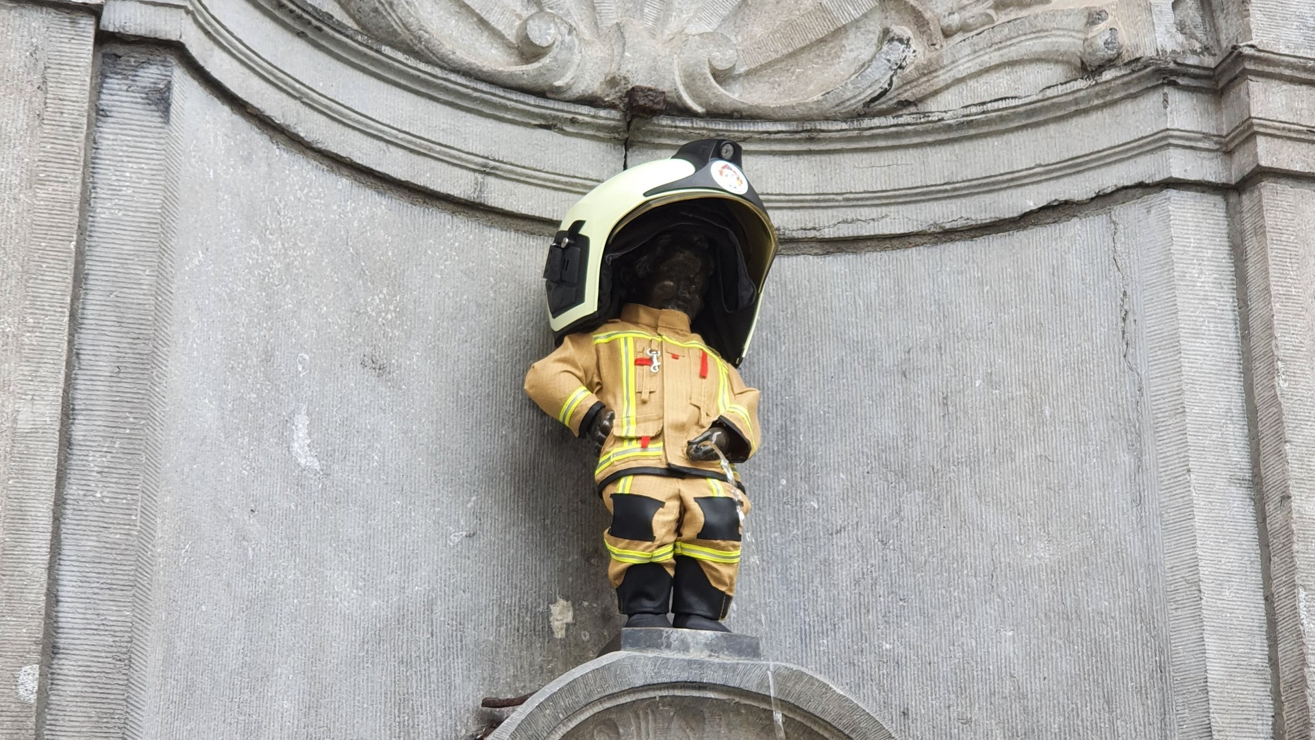 Estatua del Manneken Pis vestido de bombero con casco y uniforme en Bruselas