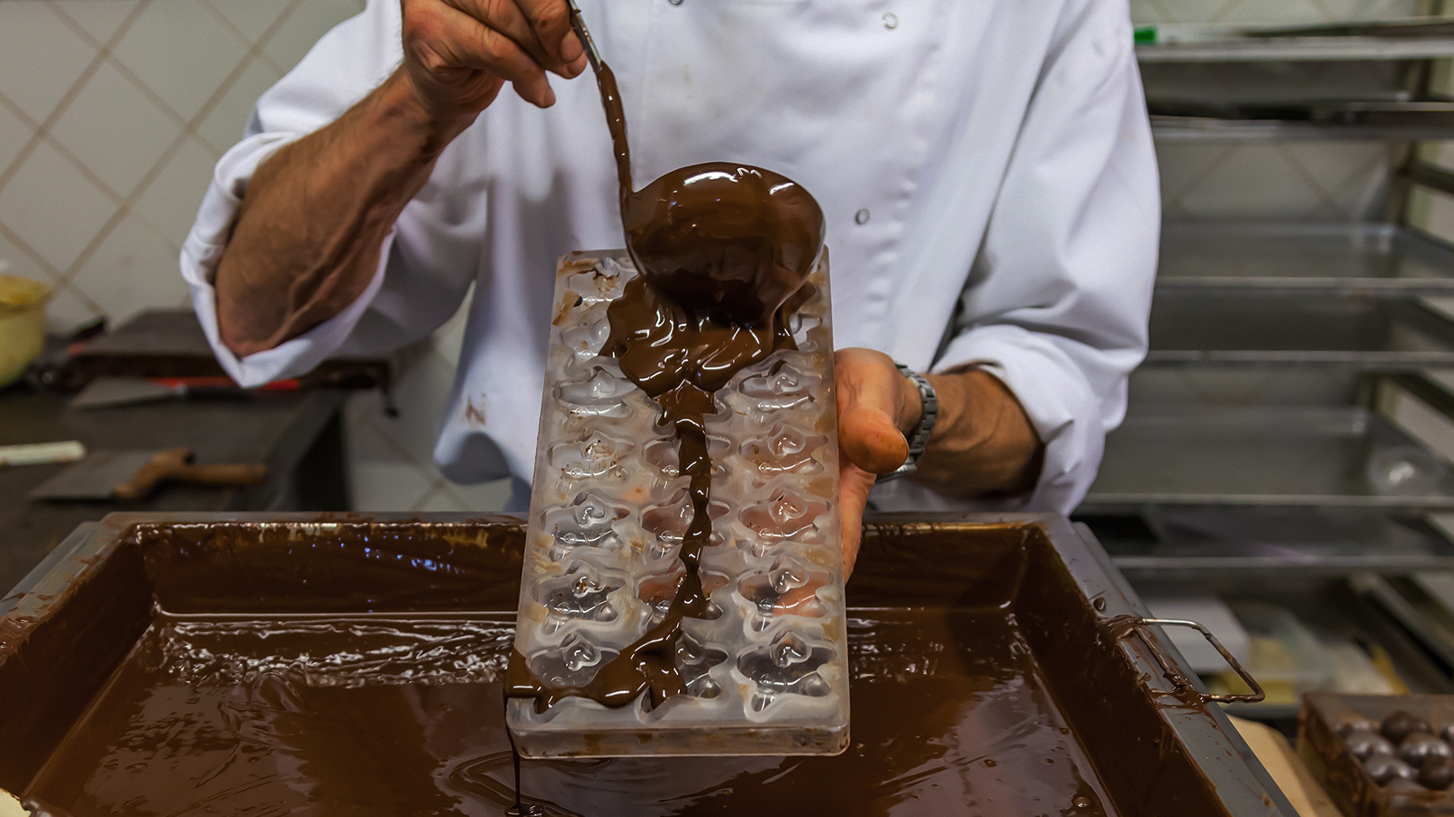 Maestro chocolatero vertiendo chocolate fundido en moldes. 