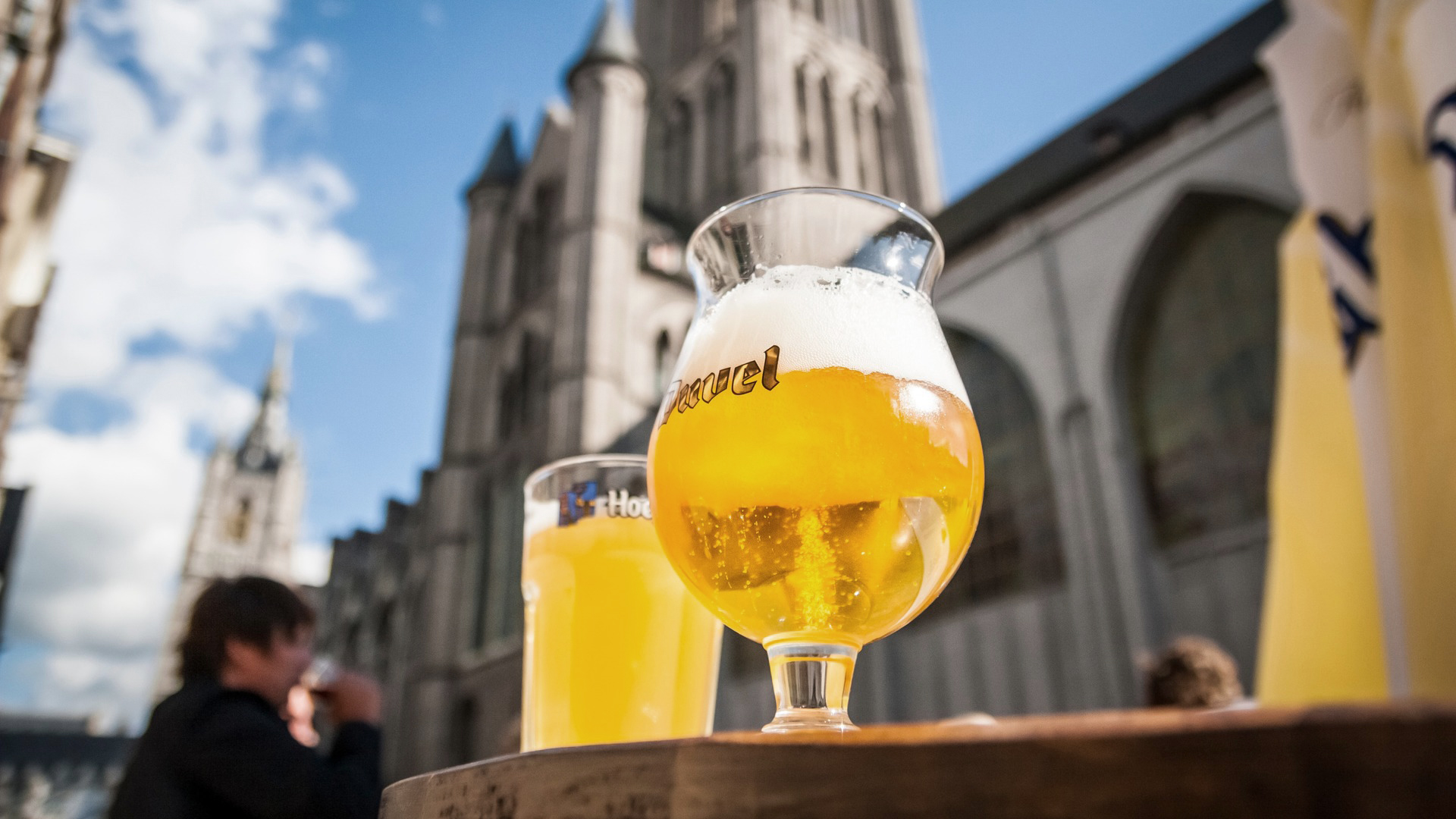 Copa de cerveza en una mesa, con edificios de fondo