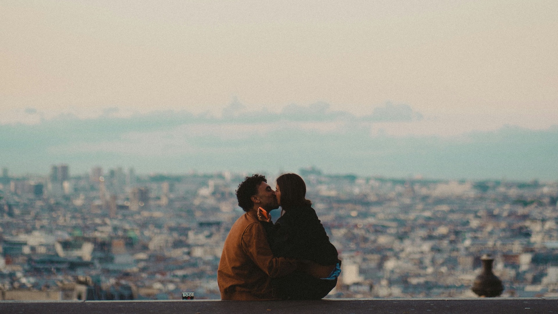 Pareja besándose al atardecer en Montmartre con vistas panorámicas de París.