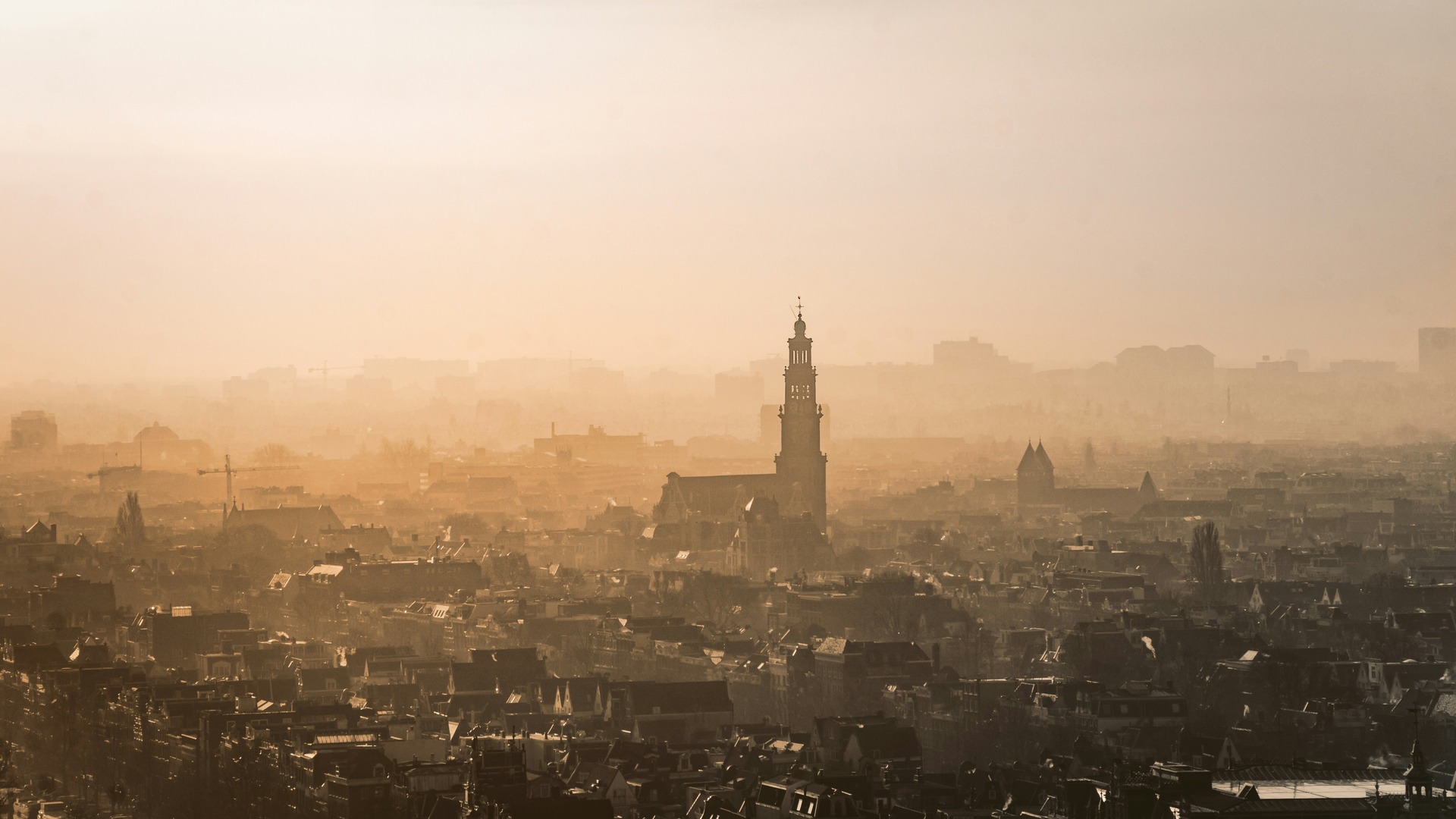 Panorámica aérea de Ámsterdam con niebla cálida y la silueta de la Westerkerk.