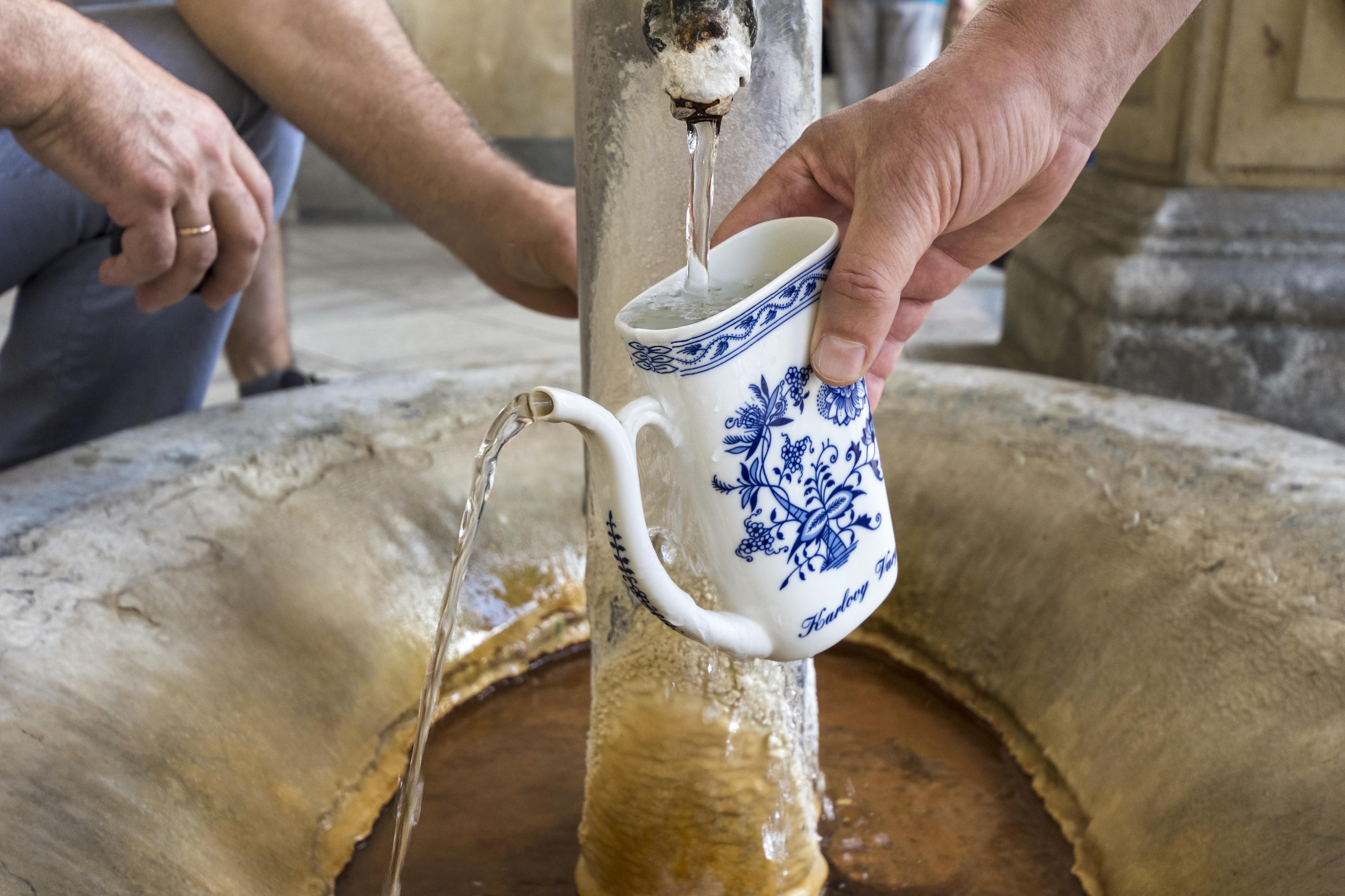 taza de pocelana llenándose en fuente de Karlovy Vary