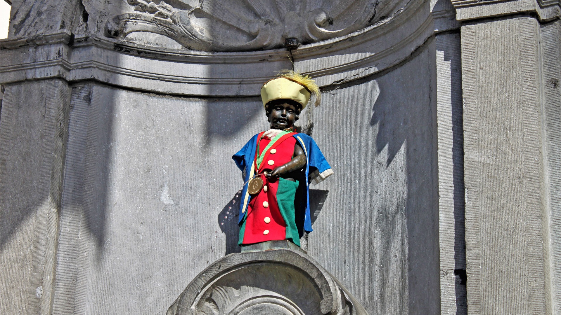 Estatua del Manneken Pis vestido con traje regional en su fuente de Bruselas.